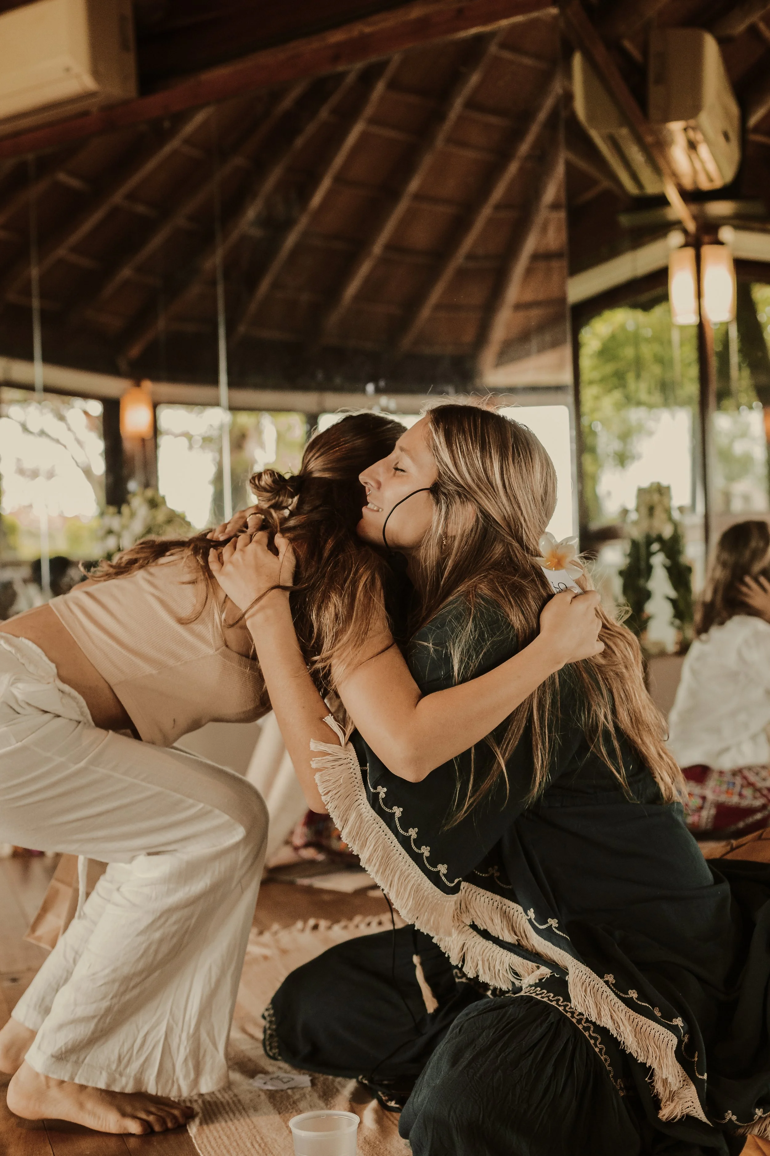 Dos mujeres abrazándose y sonriendo en un ambiente cálido y bien iluminado.