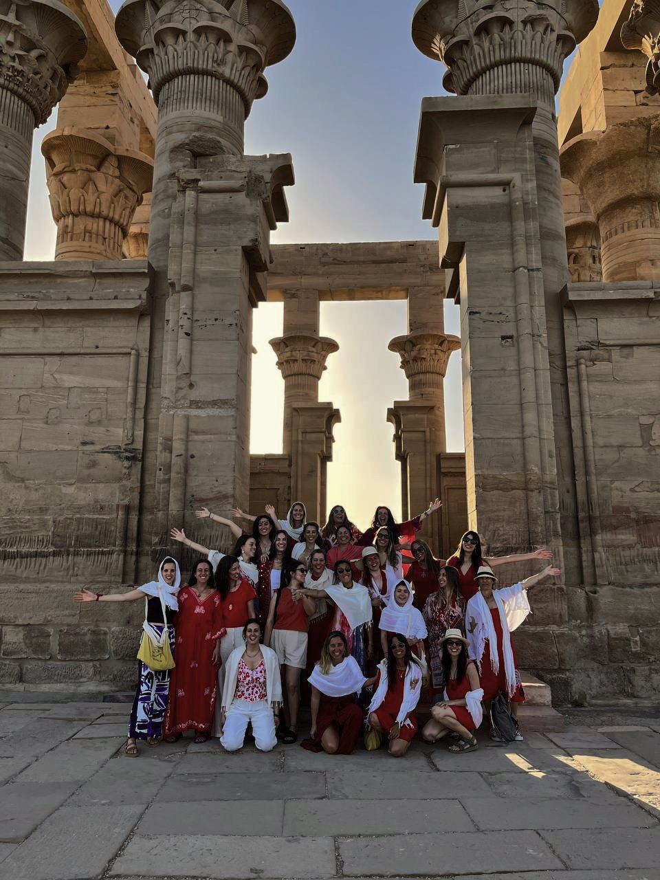 Grupo de personas en la entrada del Templo de Karnak en Egipto, con columnas antiguas de piedra y cielo despejado al fondo.