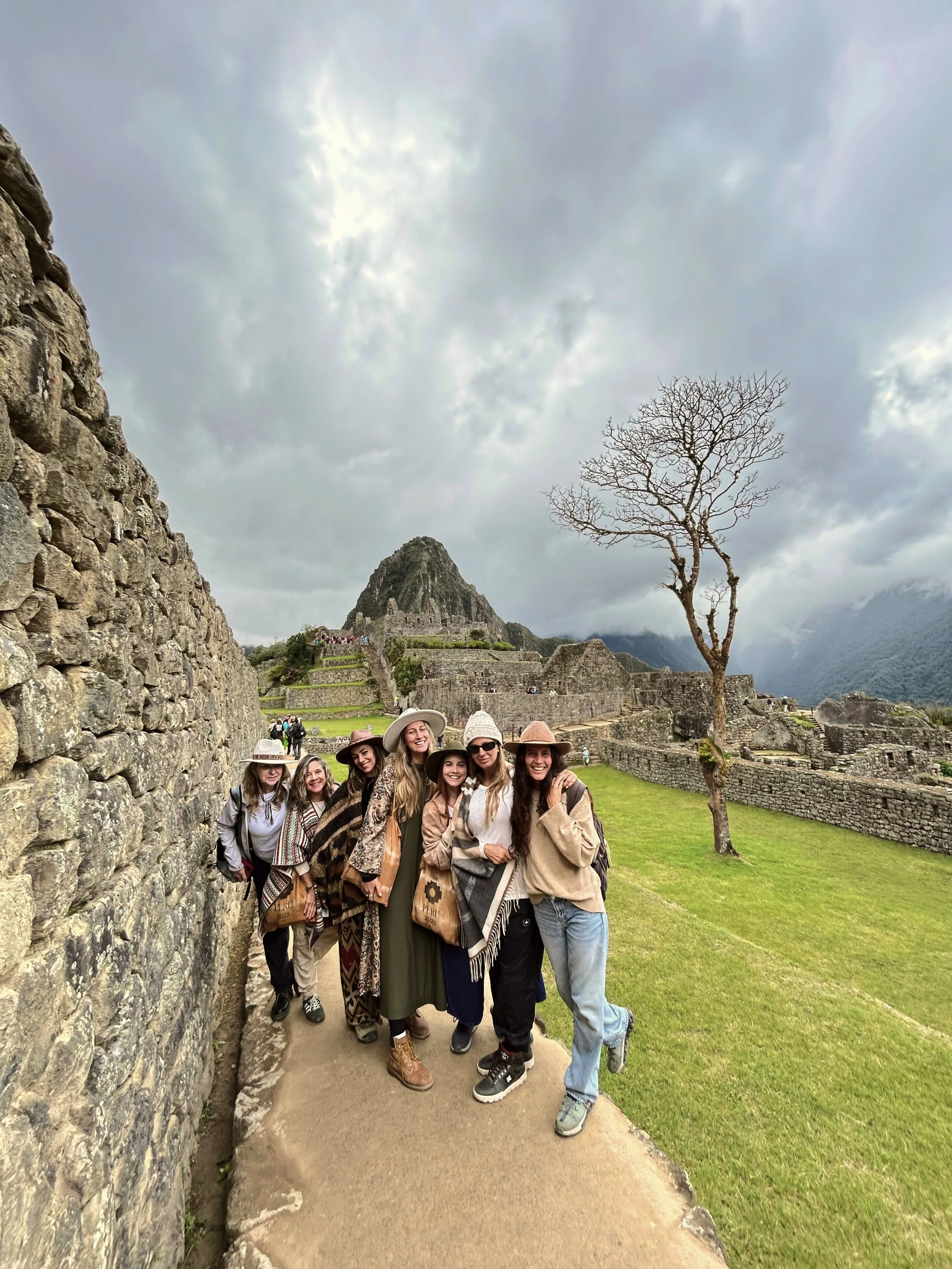 Grupo de turistas en Machu Picchu con ruinas y montañas en el fondo