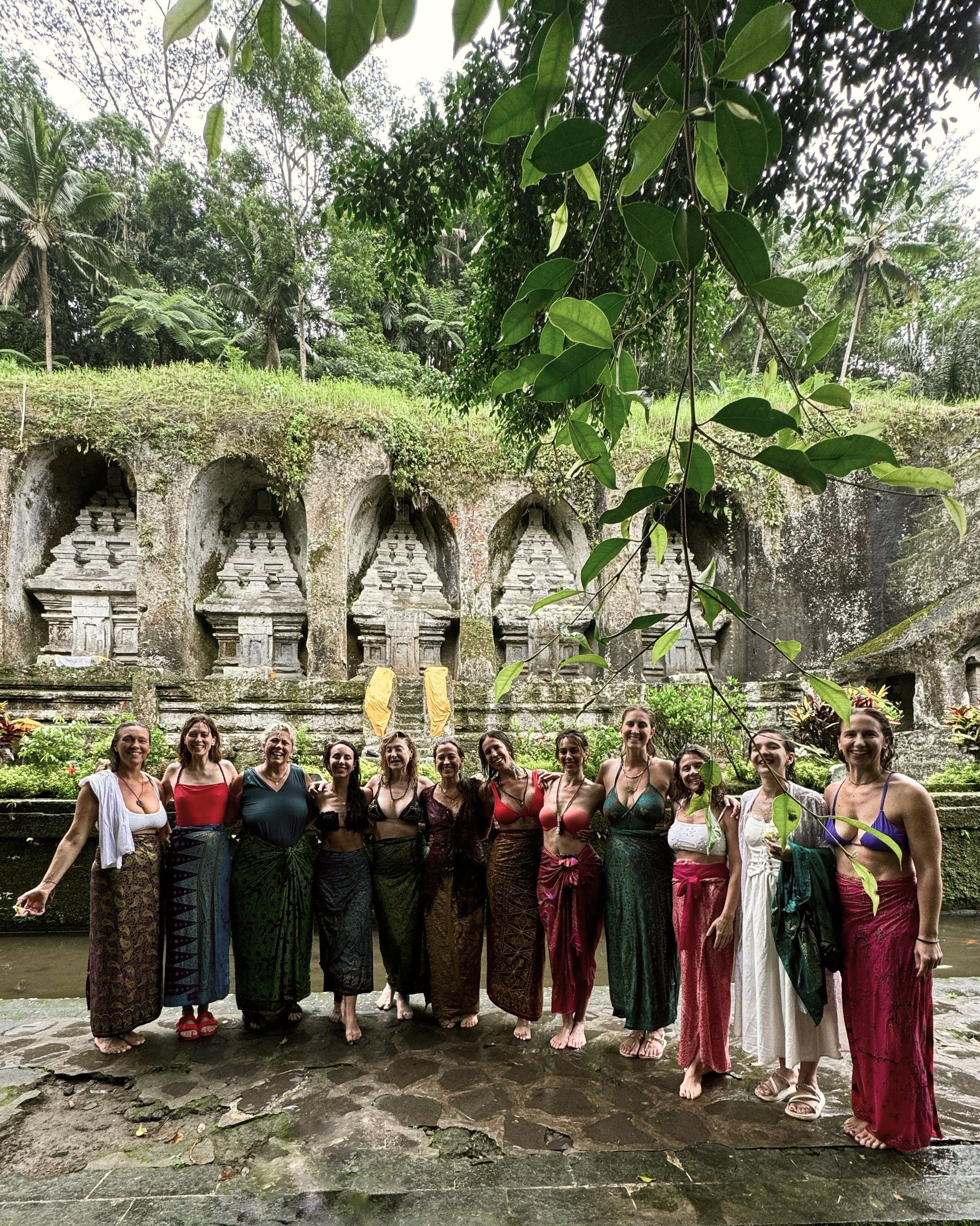 Grupo de mujeres vestidas con ropa tradicional en un lugar histórico rodeado de naturaleza y estructuras antiguas en la roca.