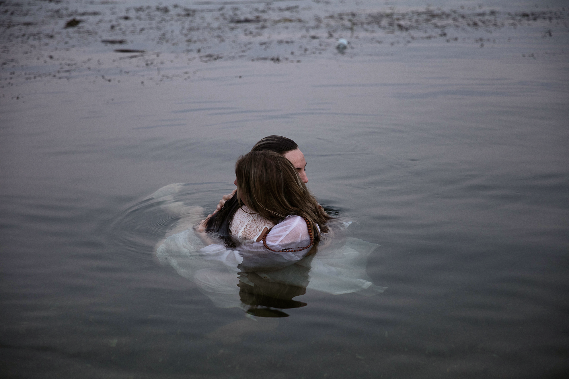 Dos personas abrazándose en el agua en un entorno natural