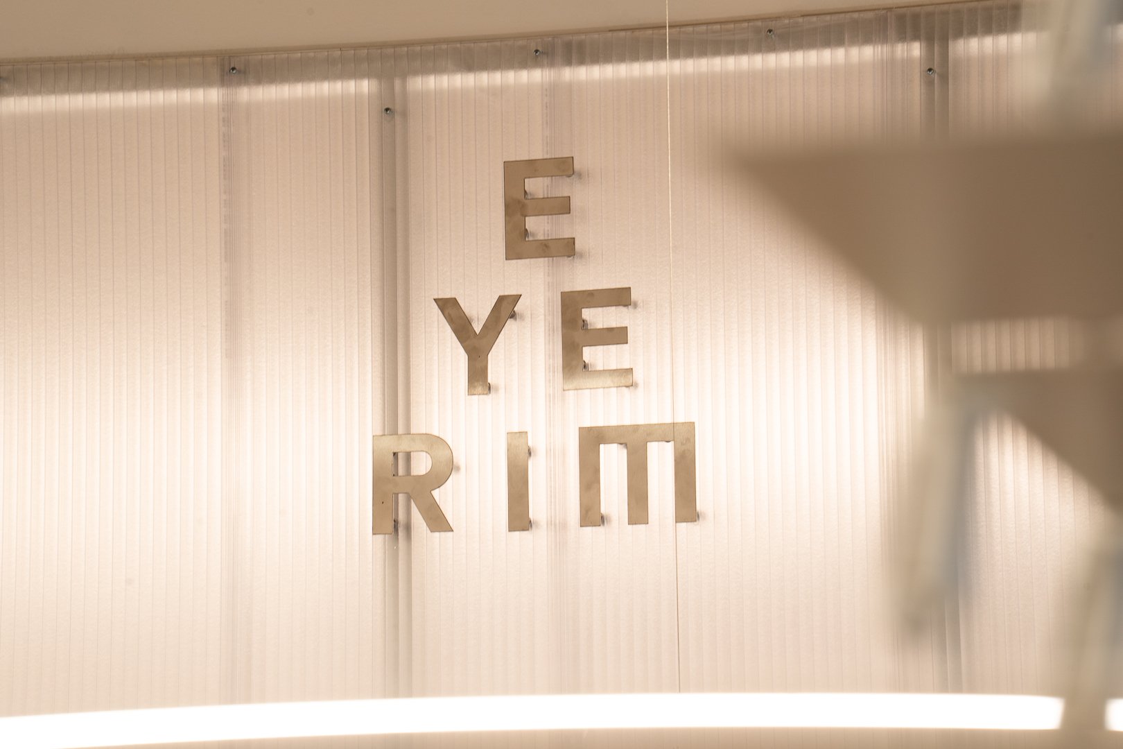 Kovový nápis EYERIM umiestnený na stenovom paneli v interiéri.