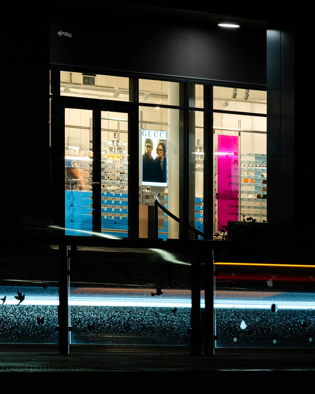 View of a brightly lit Gucci store at night through a glass window.