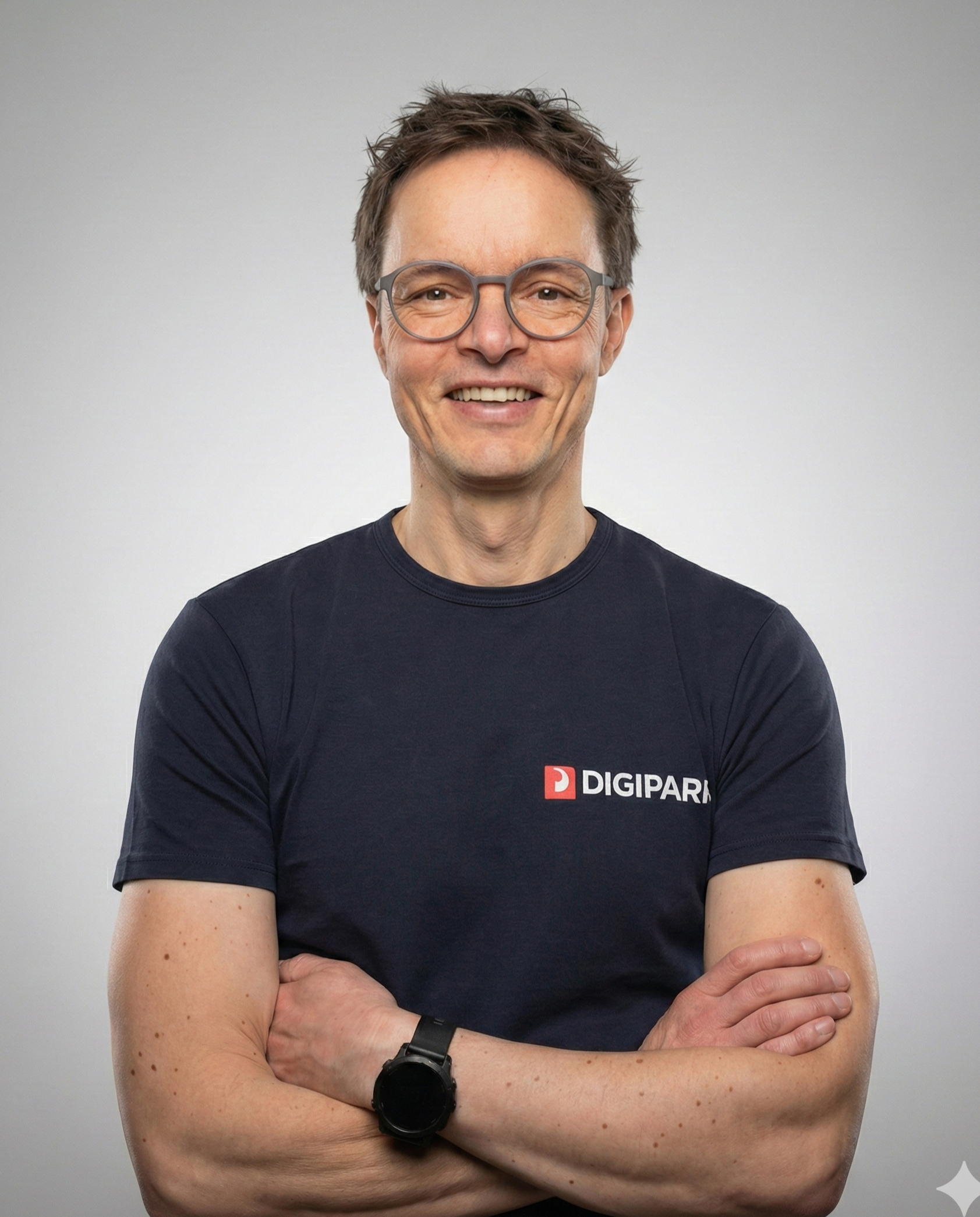 Thomas Stebich, DIGIPARK Gründer und Geschäftsführer. Ein Mann mit dunkelblonden Haaren, blauem T-Shirt mit DIGIPARK-Logo auf der Brust, verschränkten Armen vor grauem Hintergrund.