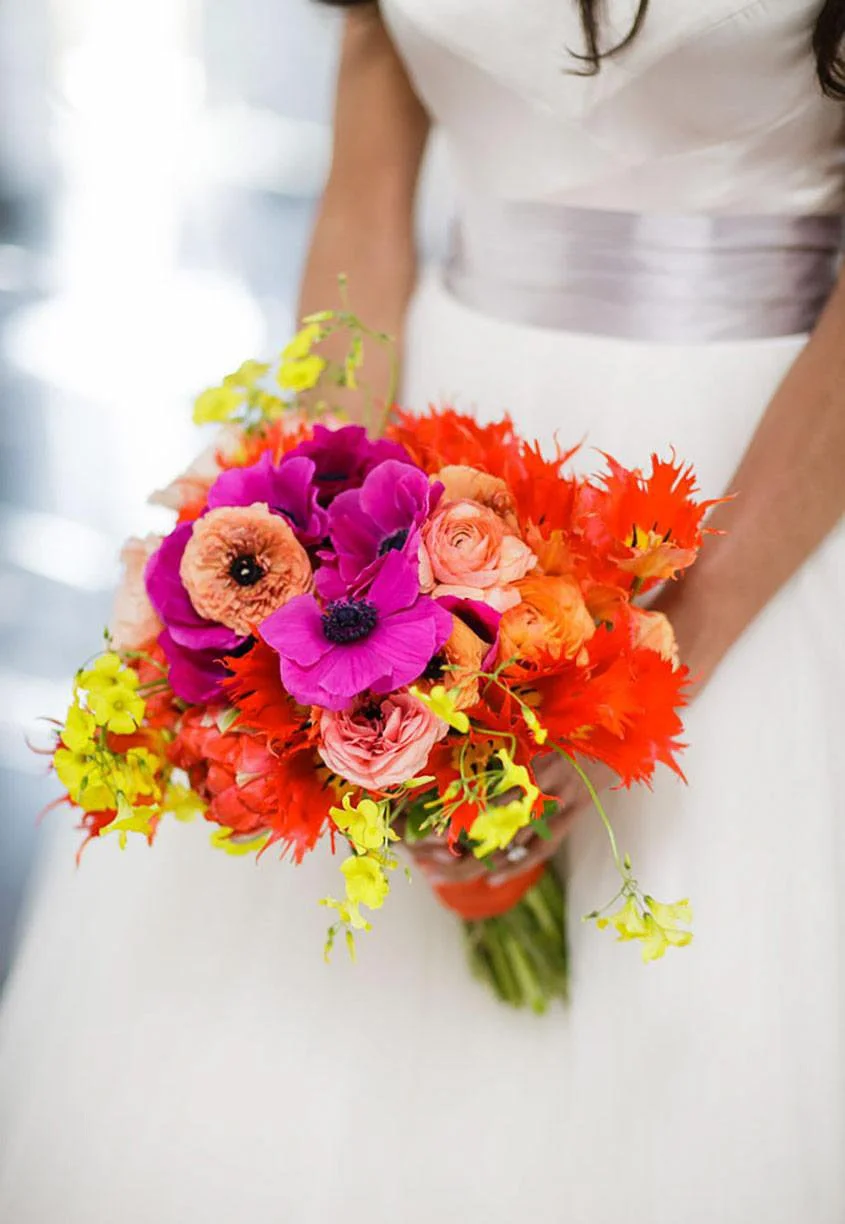 A woman in a white dress holding a colorful bouquet of flowers.