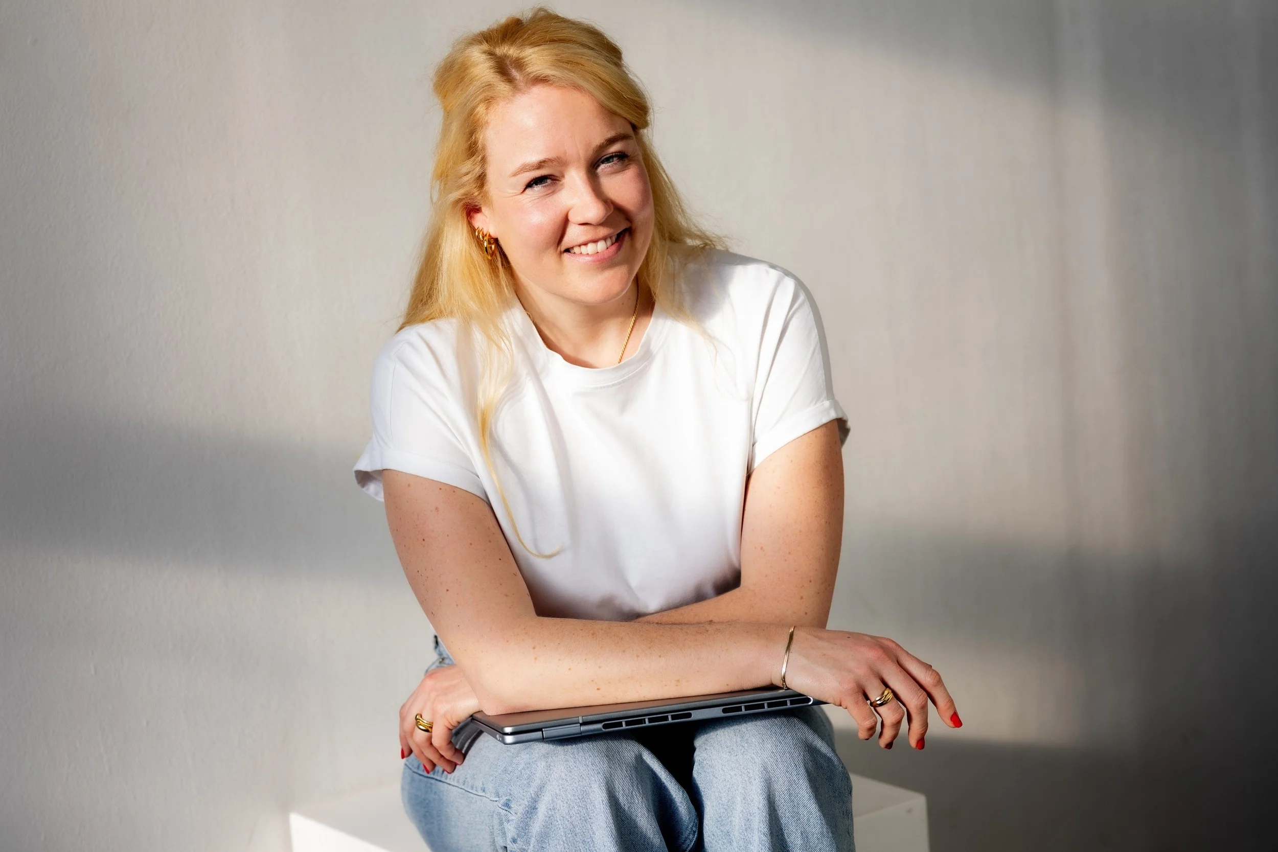 Marie sitzt auf einem weissen Hocker mit ihrem Laptop auf dem Schoss