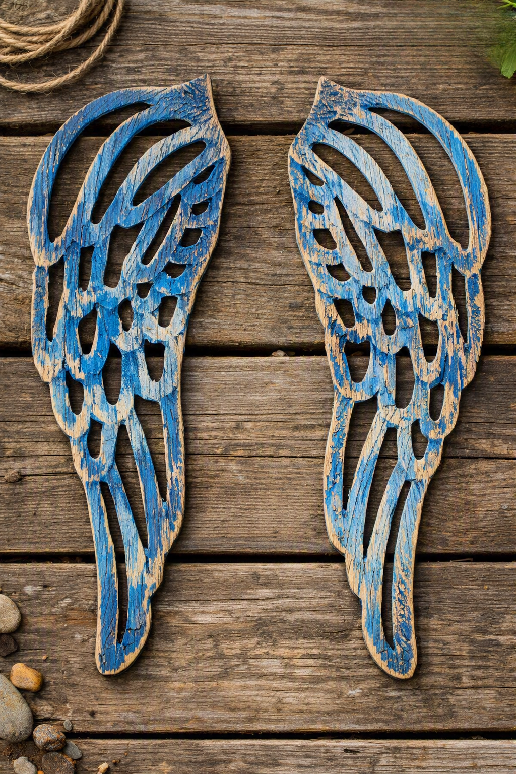 Decorative wooden angel wings painted in blue, laid on a wooden surface.