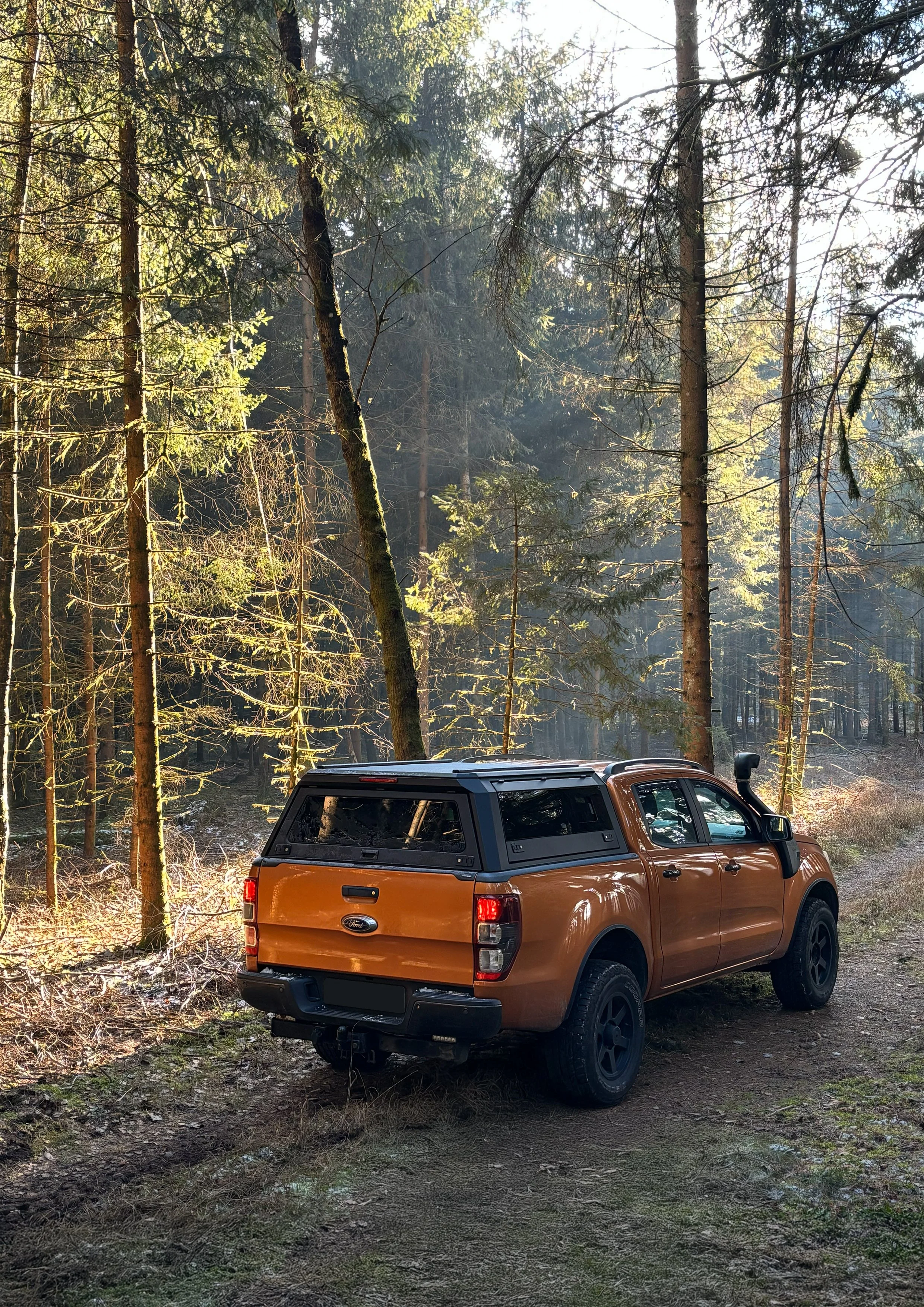 A black Toyota Tundra pickup truck driving on a dusty, rocky terrain with dust being kicked up by its tires, in a desert landscape with rock formations in the background.