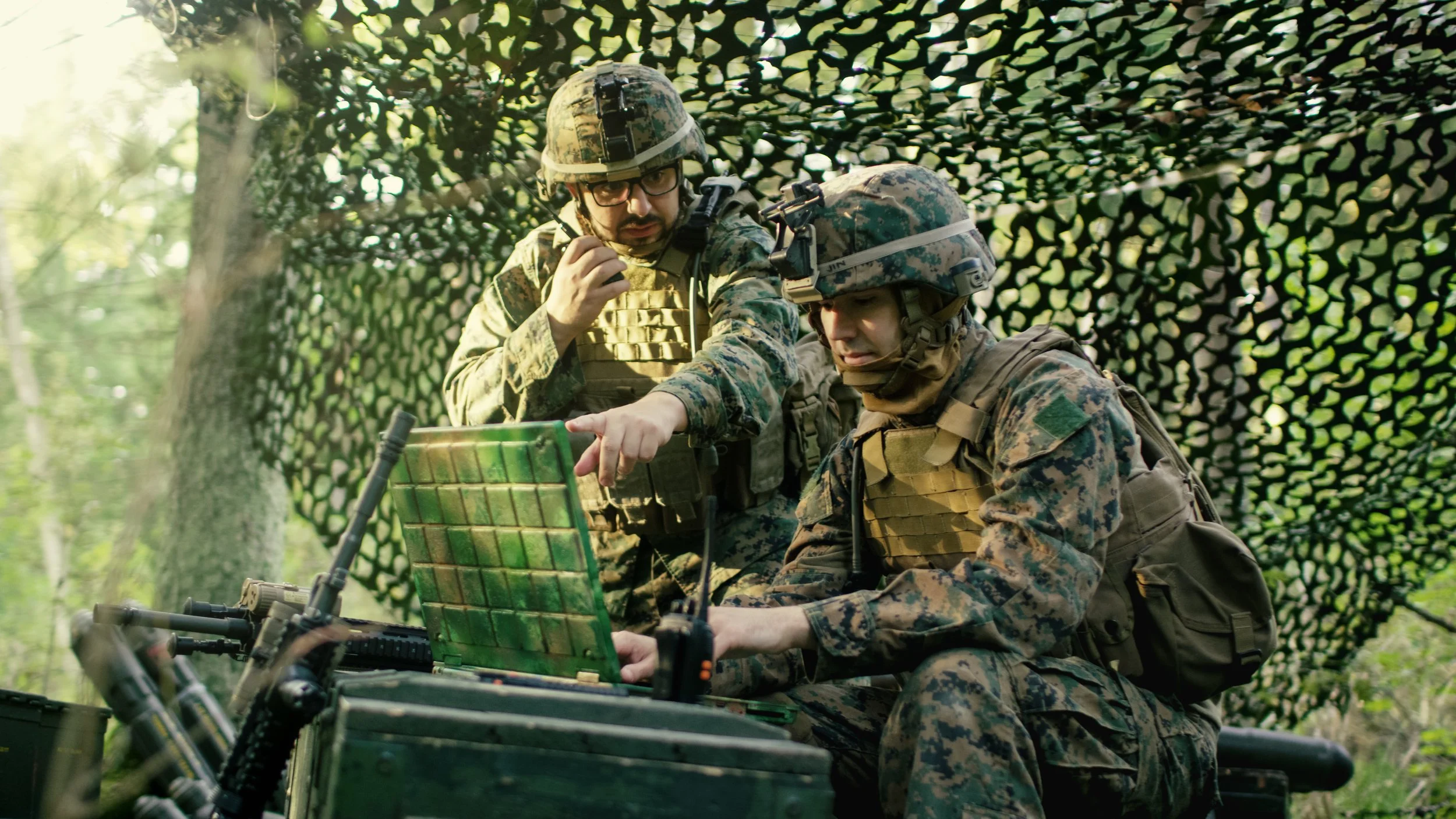Two soldiers in green using laptop and mobile phone