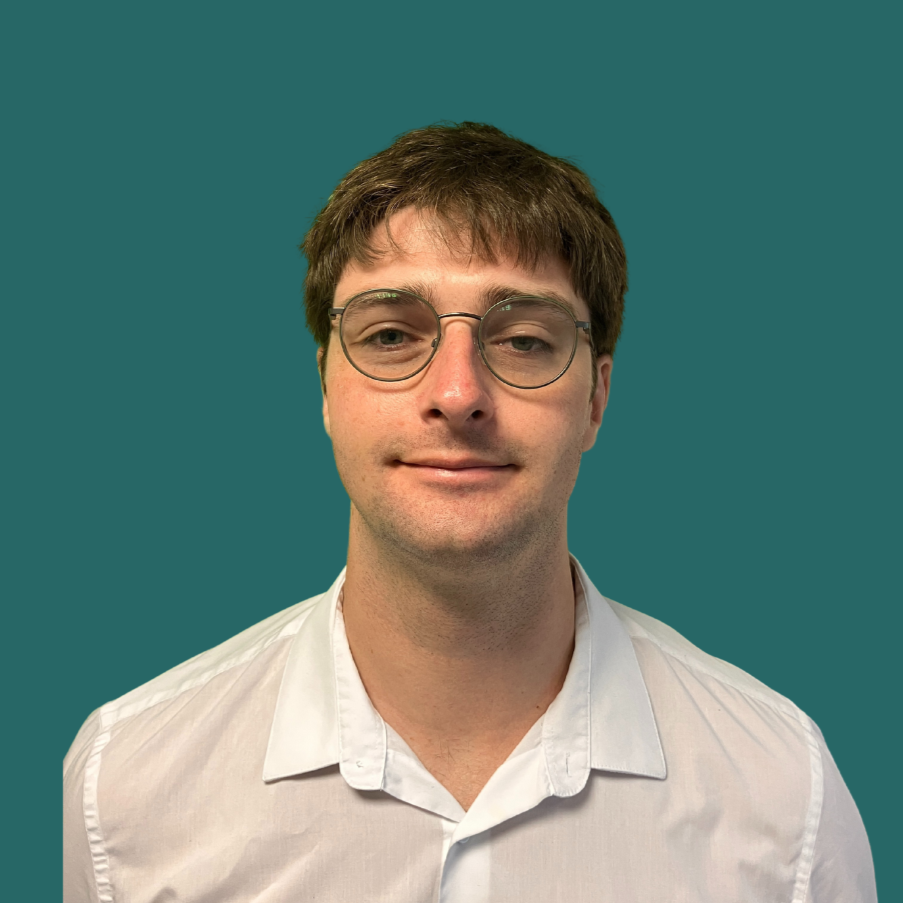 A young man with brown hair, wearing glasses, and a white shirt, smiling slightly, against a teal background.