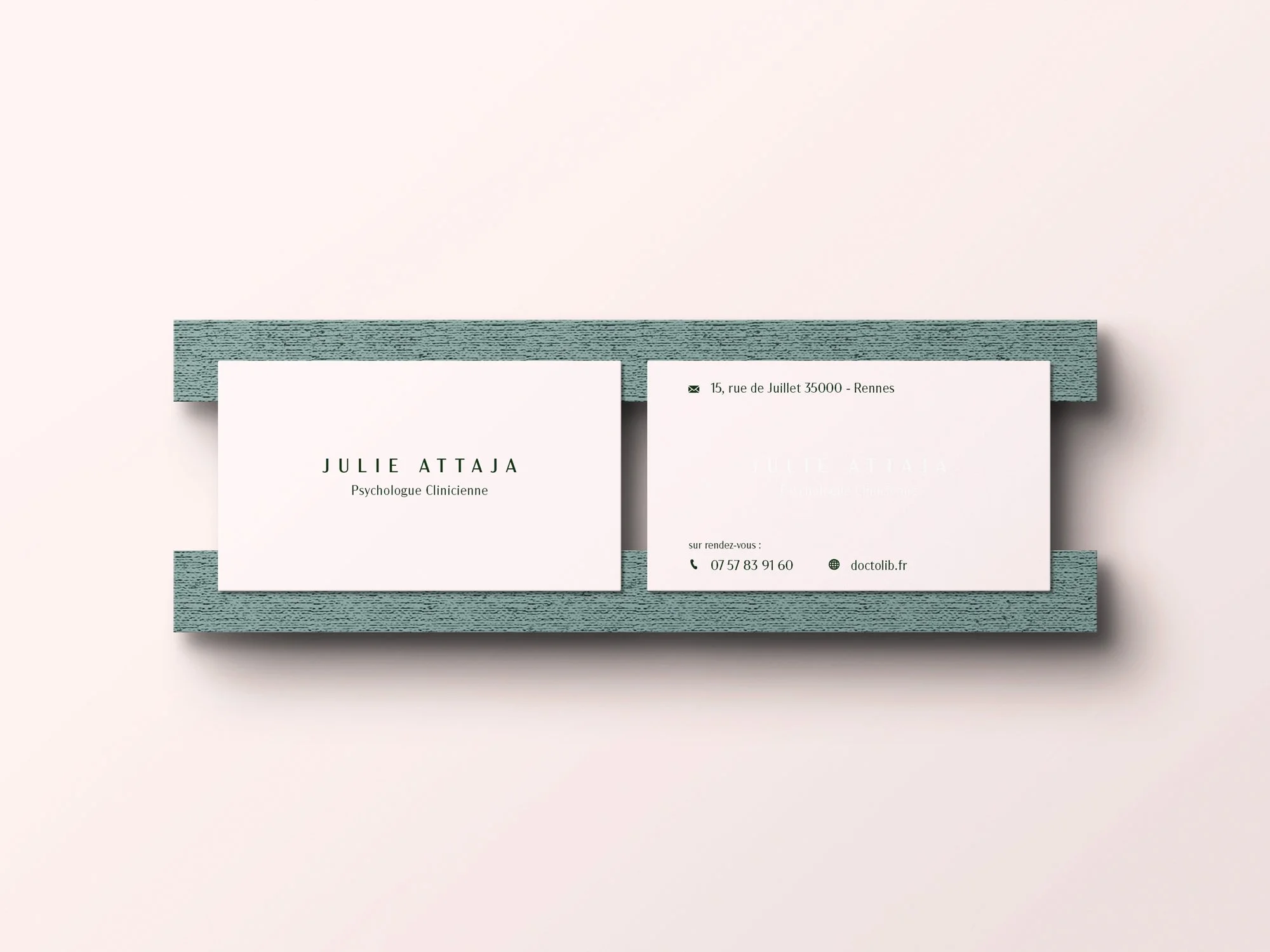 Carte de visite blanche avec nom et titre, posée sur une étagère en bois gris, avec une autre carte montrant une adresse, un téléphone et un site web.