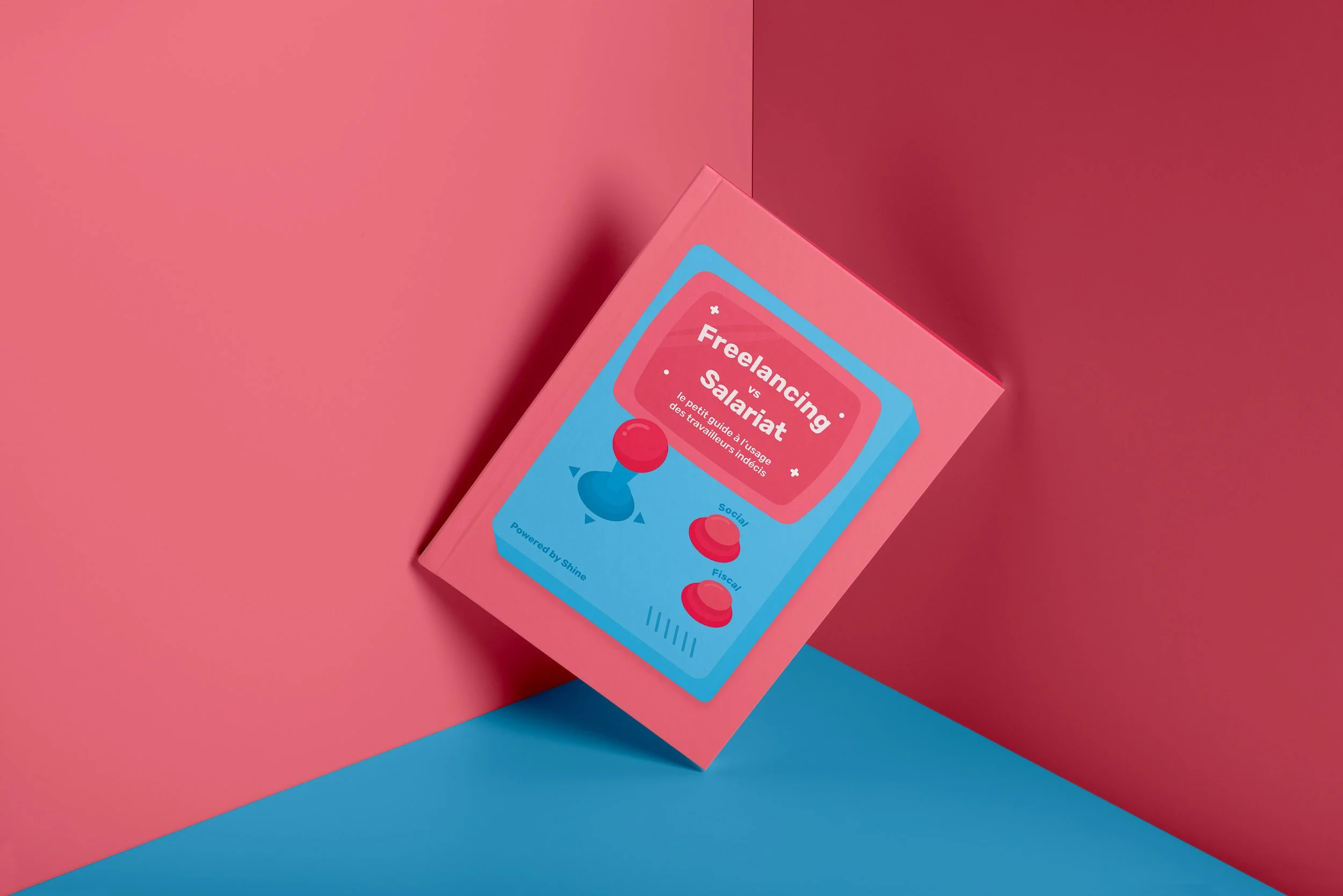 Boîte rose avec illustration de joystick numérique Blue et boutons rouge et vert, intitulée 'Freelancing vs Salariat: Le petit guide à l'usage des travailleurs indécis', sur fond rose et bleu.
