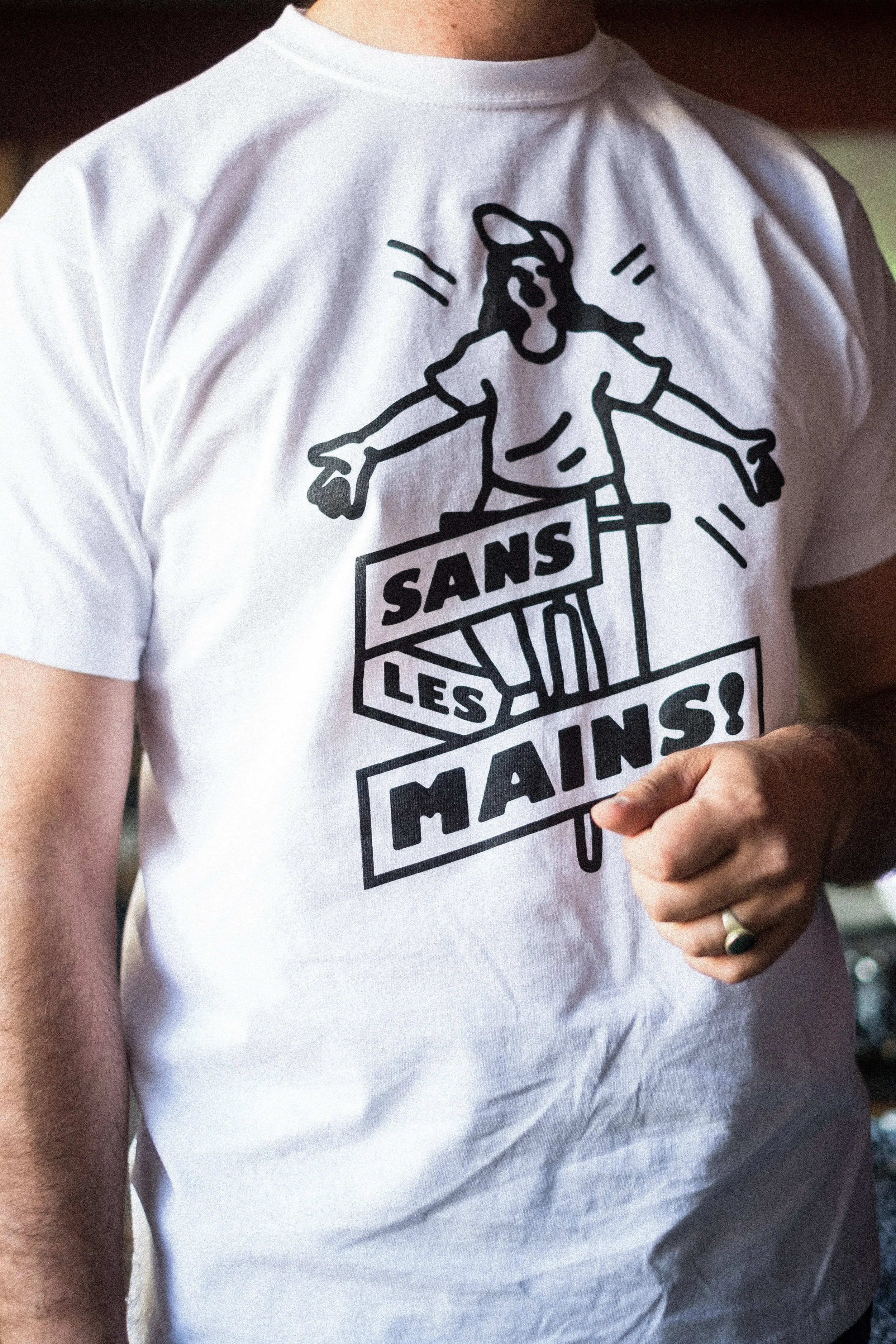 T-shirt blanc avec dessin d'une personne de style cartoon et texte 'SANS LES MAINS!' ©GuillaumeBlot