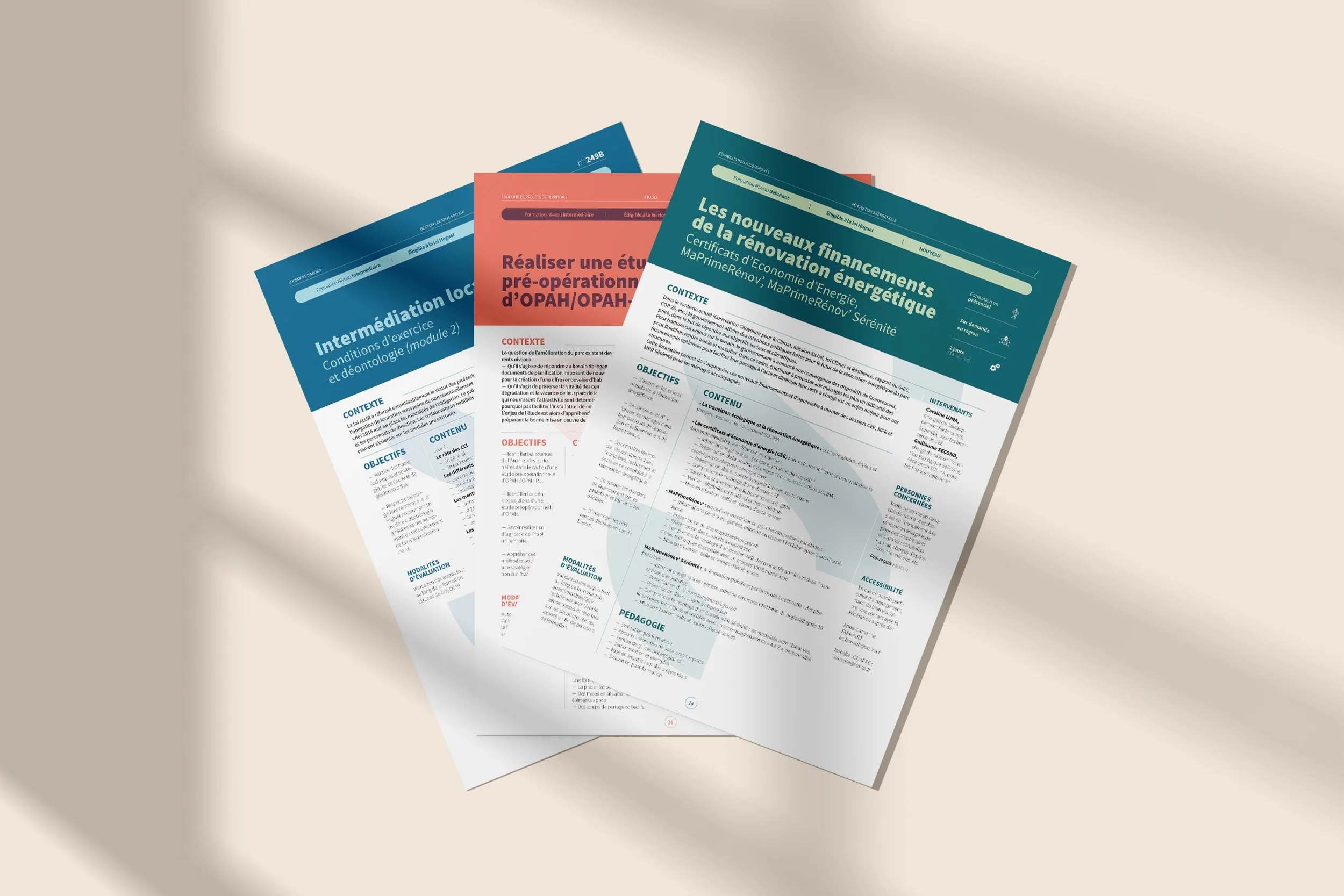 Trois documents pédagogiques étalés sur une surface claire, avec du texte en français sur l'intermédiation locale, la rénovation énergétique, et la préparation pré-opératoire, en couleur bleue, rouge et vert. Une ombre douce est visible à gauche.
