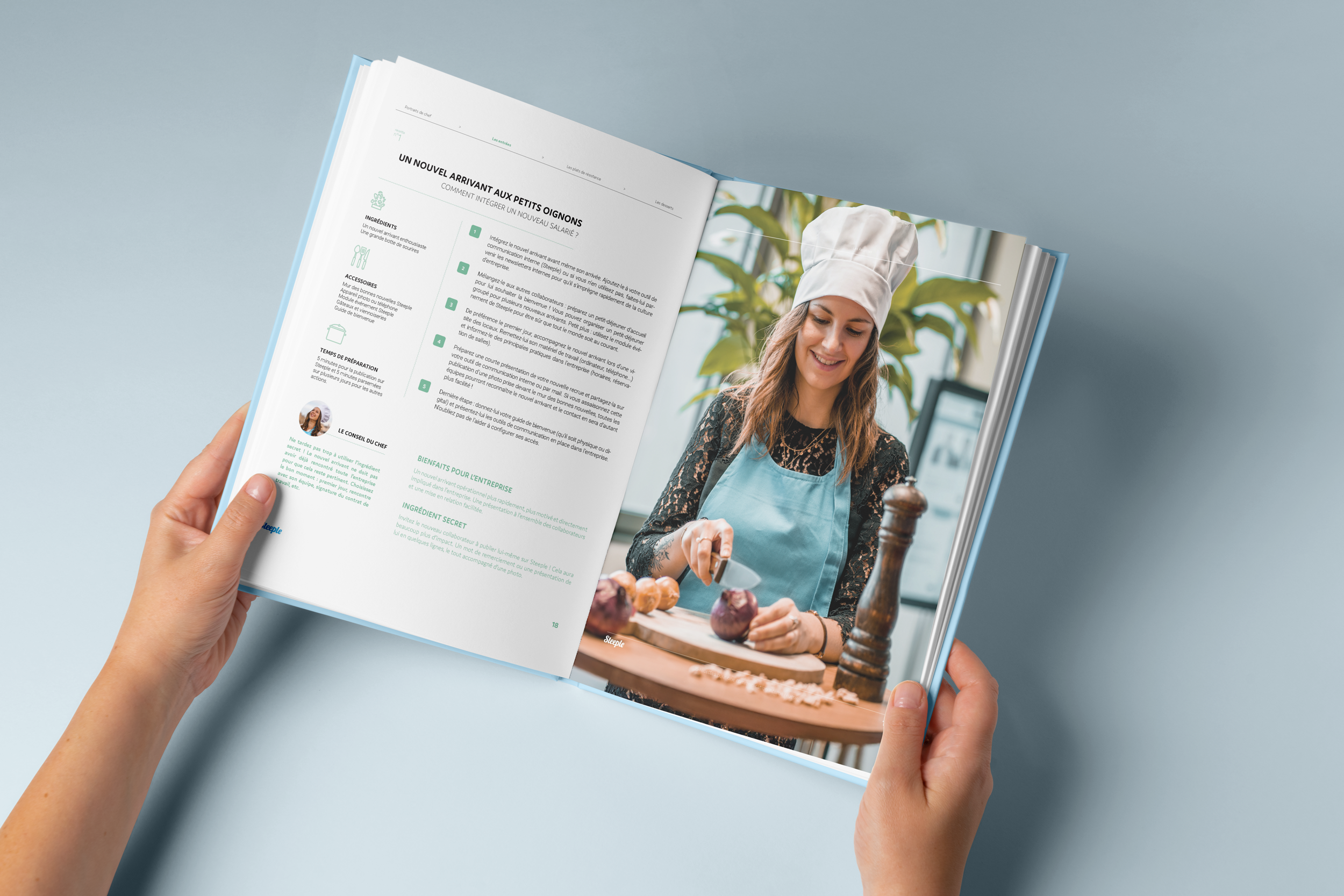 Une femme en toque de chef et tablier bleu coupe des oignons sur un plan de travail en bois, dans une cuisine lumineuse.