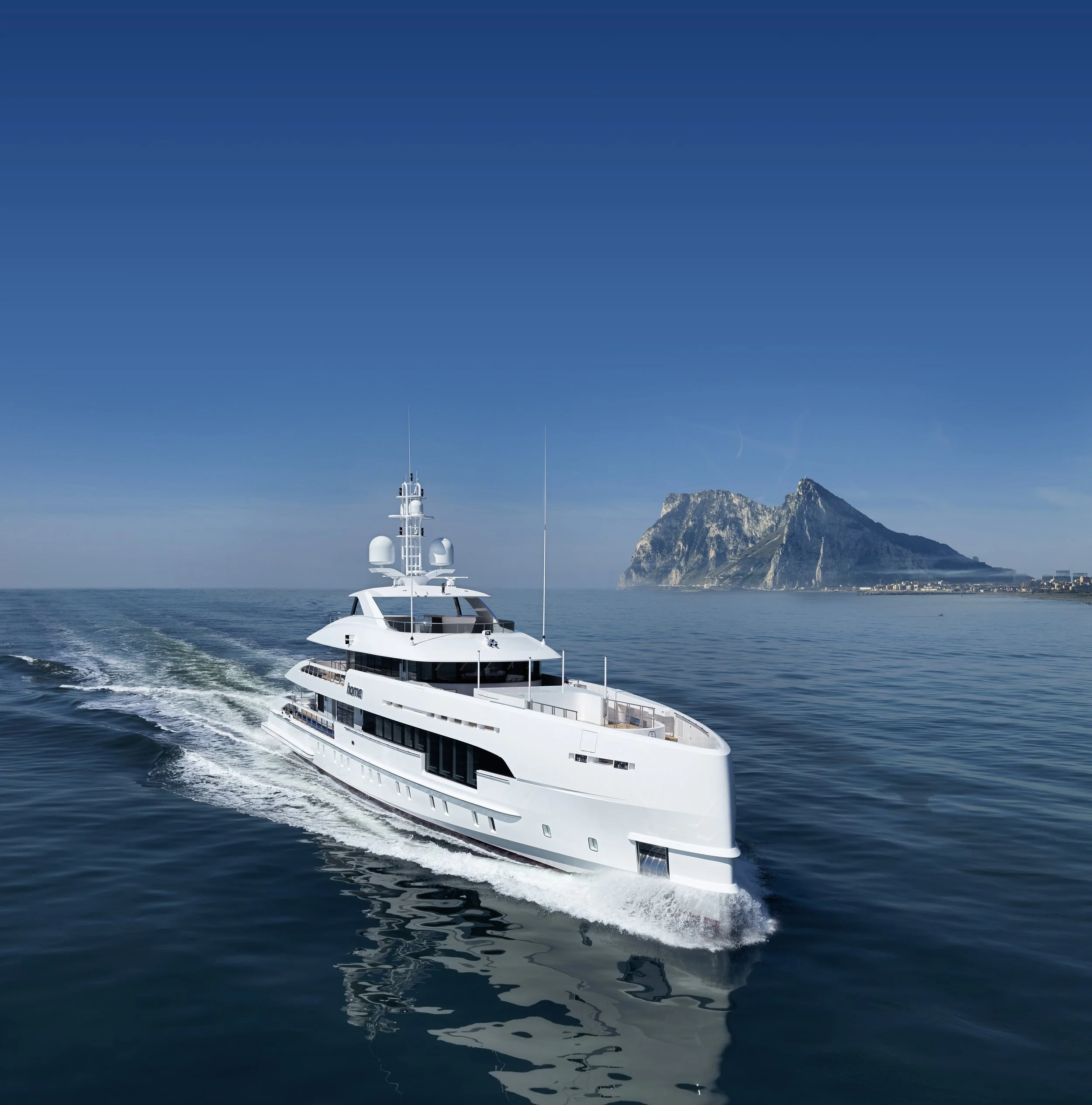 A white motor yacht sailing in calm blue waters with a mountain in the background.
