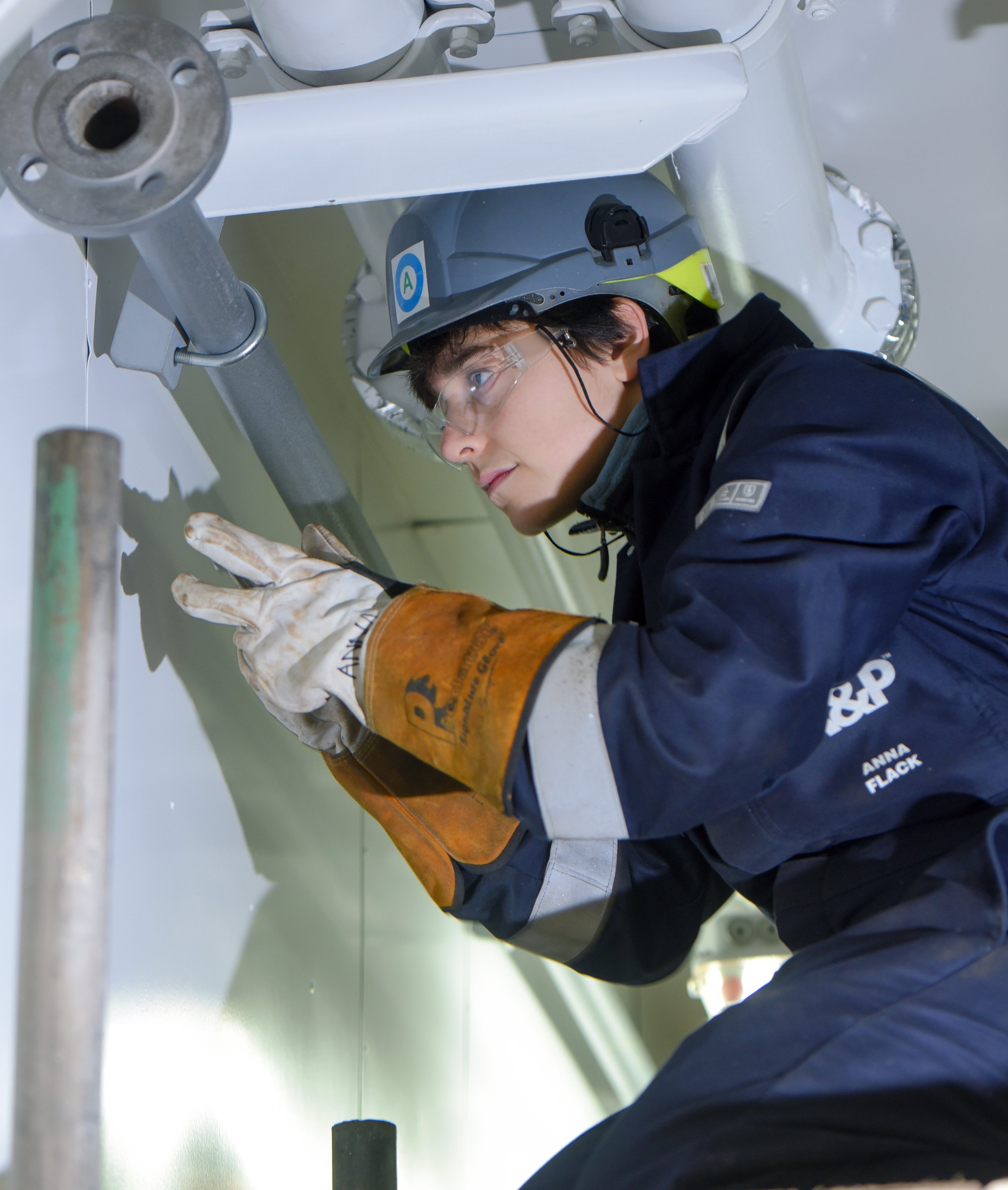 A  Balaena worker in safety gear, including a helmet and gloves, working on a large machine or industrial equipment.