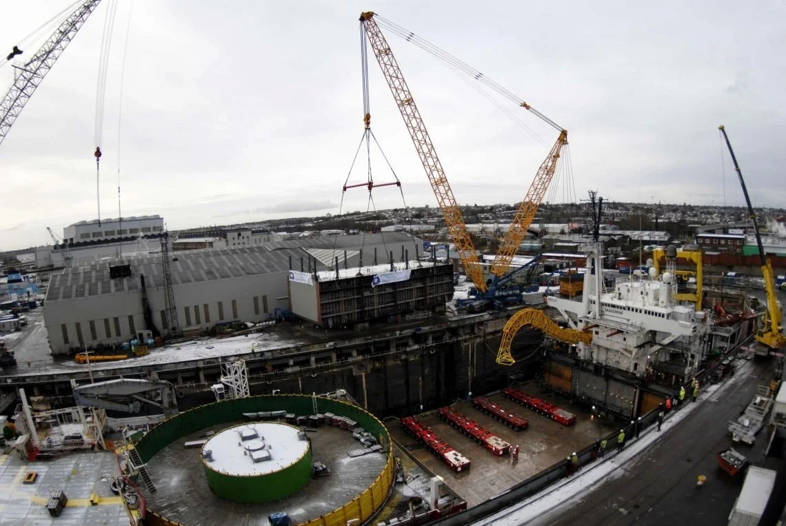 Construction site with cranes and a large vessel under construction