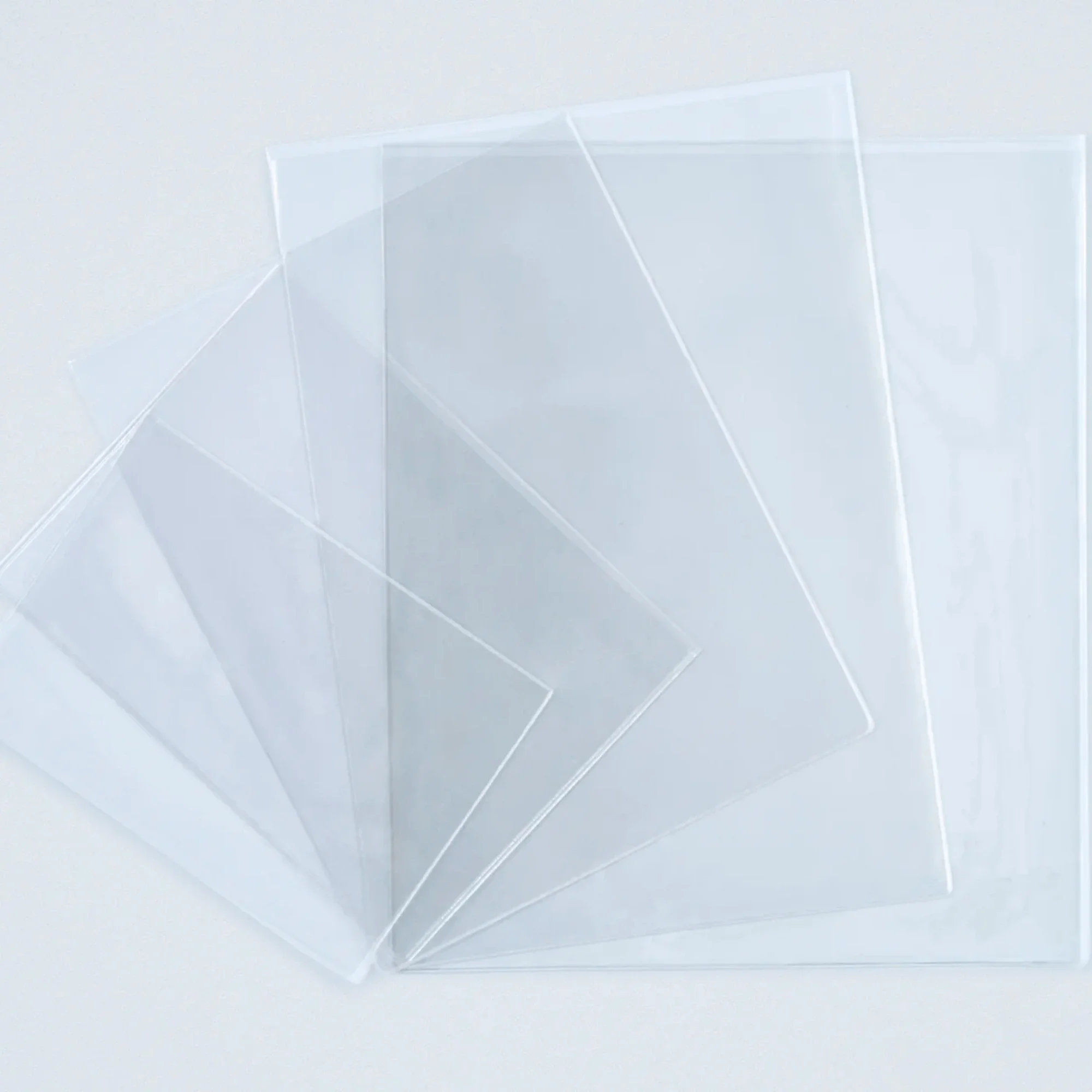 Five clear plastic sheets fanned out on a white surface.