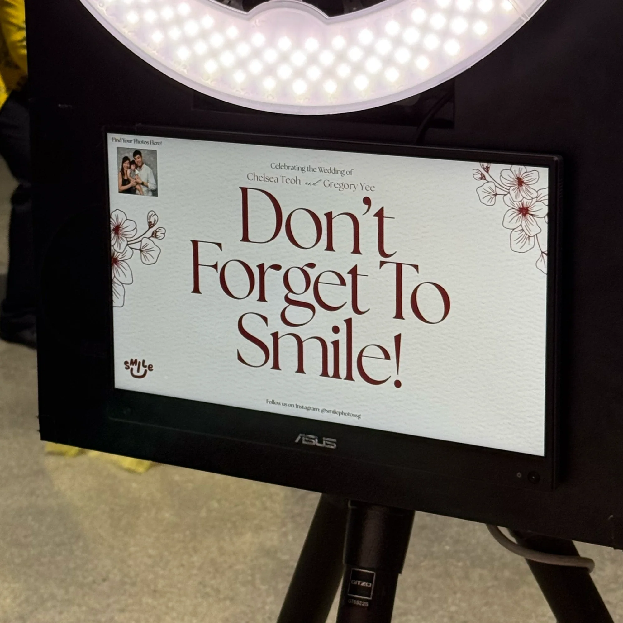 A sign with the message, 'Don't forget to smile!' with floral decorations in the corners and a small photo of a couple in the top left corner.