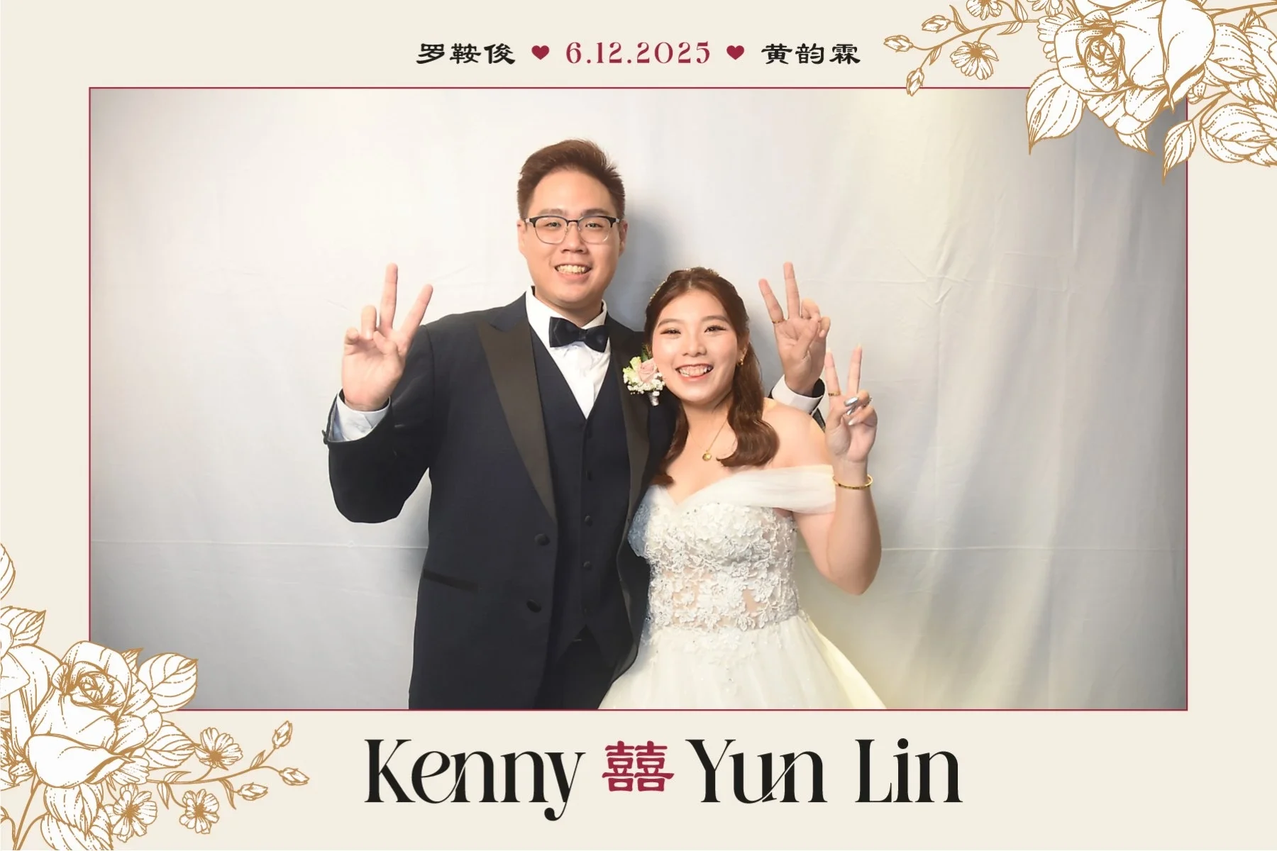 A happy bride and groom at their wedding, both smiling and making peace signs. The groom wears a black tuxedo with a bow tie, and the bride wears a white lace wedding gown with off-the-shoulder sleeves. The background features a plain, light-colored 
