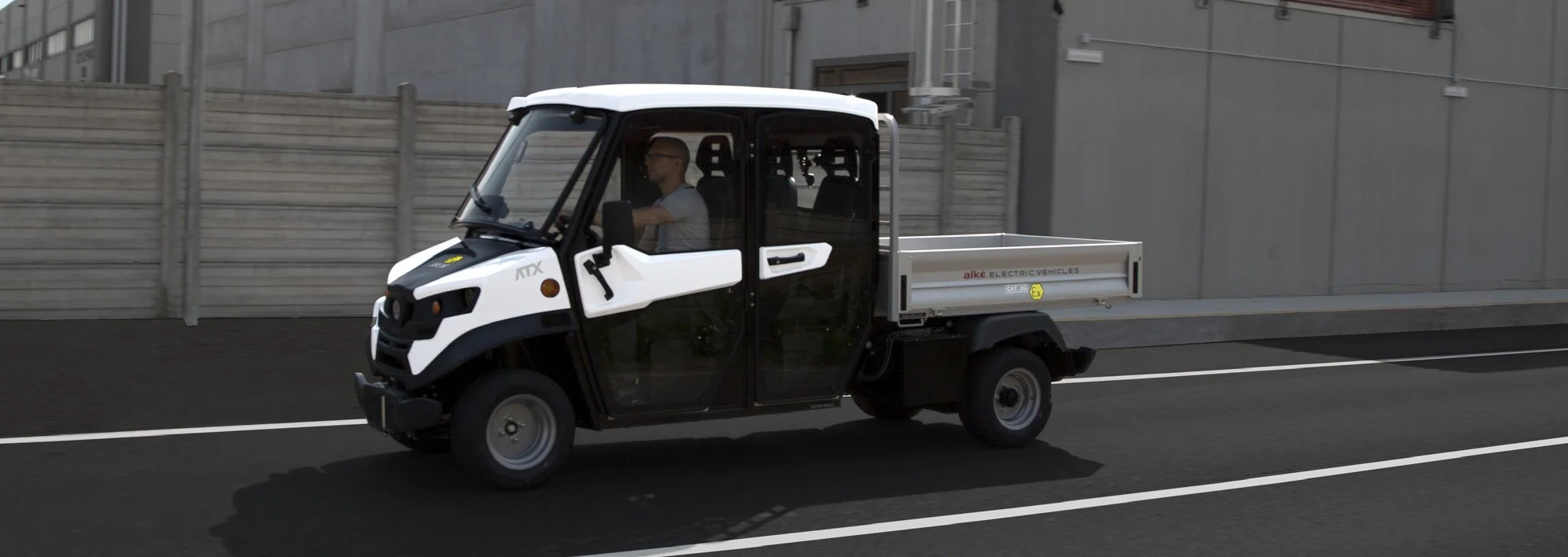 En vit och svart elektrisk liten Alkè ATEX kör på en väg.
