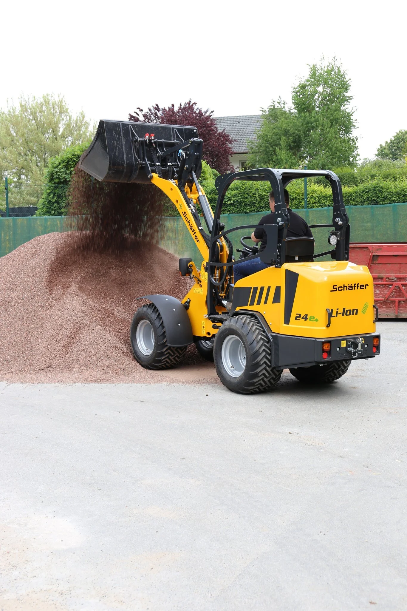 En Schäffer som flyttar en hög med grus eller sand på en gräsmatta.