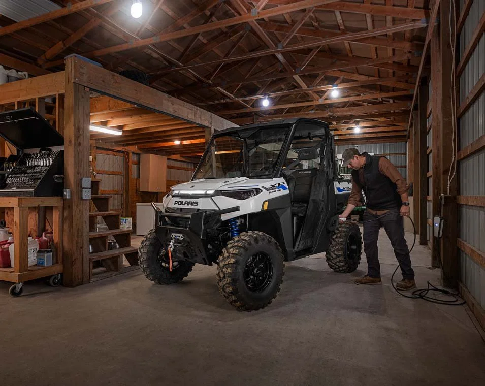 En person som kopplar ur en Polaris Ranger XP Kinetic i ett garage.