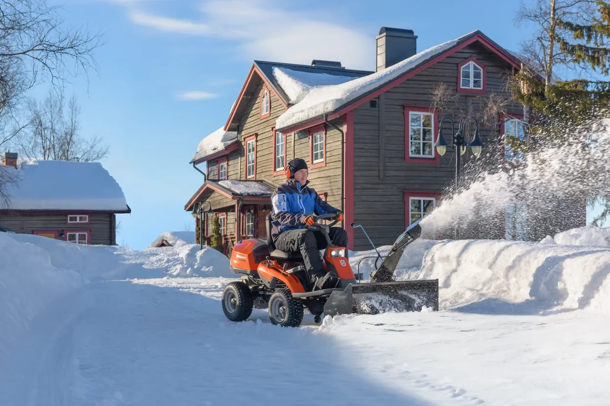 Person som kör Husqvarna Rider framför ett hus på vintern.