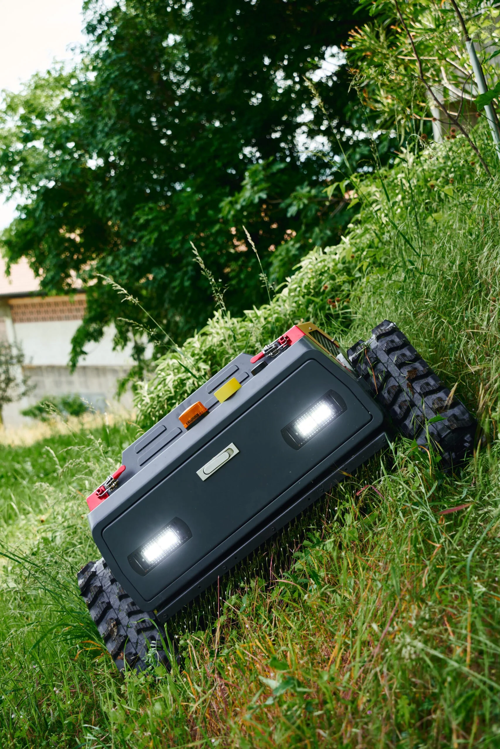 BlueBird Fjärrstyrd Släntklippare med LED-lampor och kameror, som korsar en grön gräsmatta.