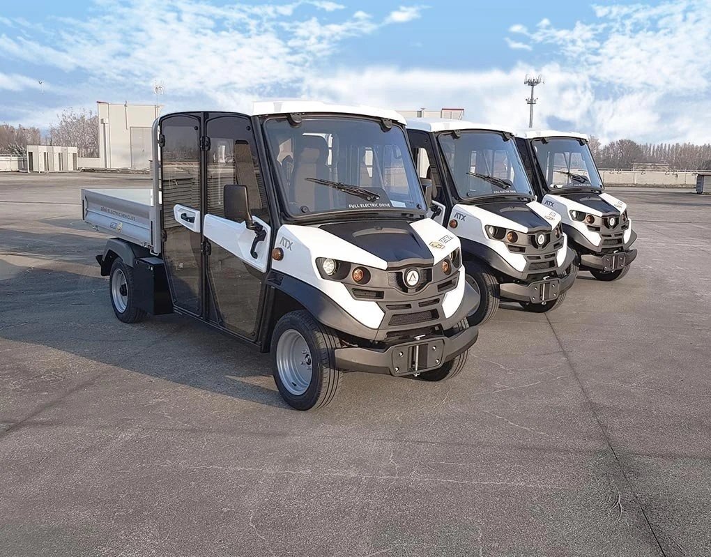 Tre elektriska Alkè parkerade i rad på en öppen torgyta under en klar himmel.