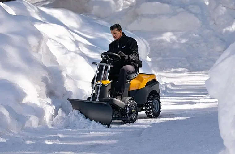 Man som kör en Stiga Park på en snötäckt väg.