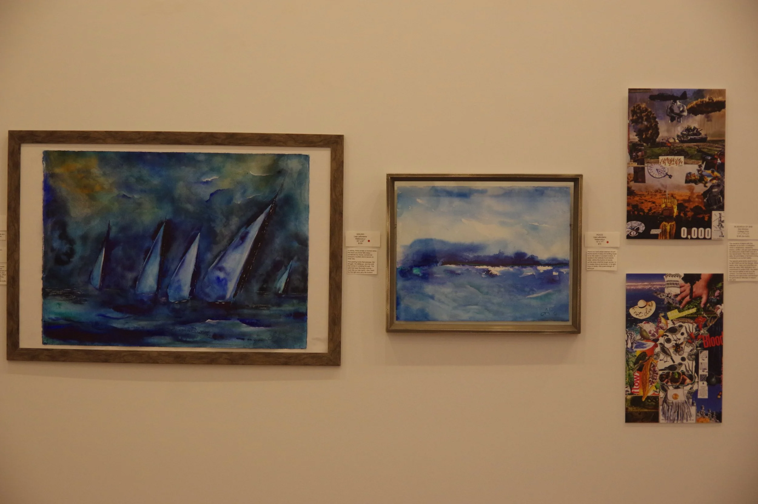 Two watercolor paintings of ocean scenes displayed on a white gallery wall, with smaller collage artworks to the right.