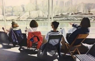 Four women sitting in a row by a large window overlooking a harbor with sailboats.
