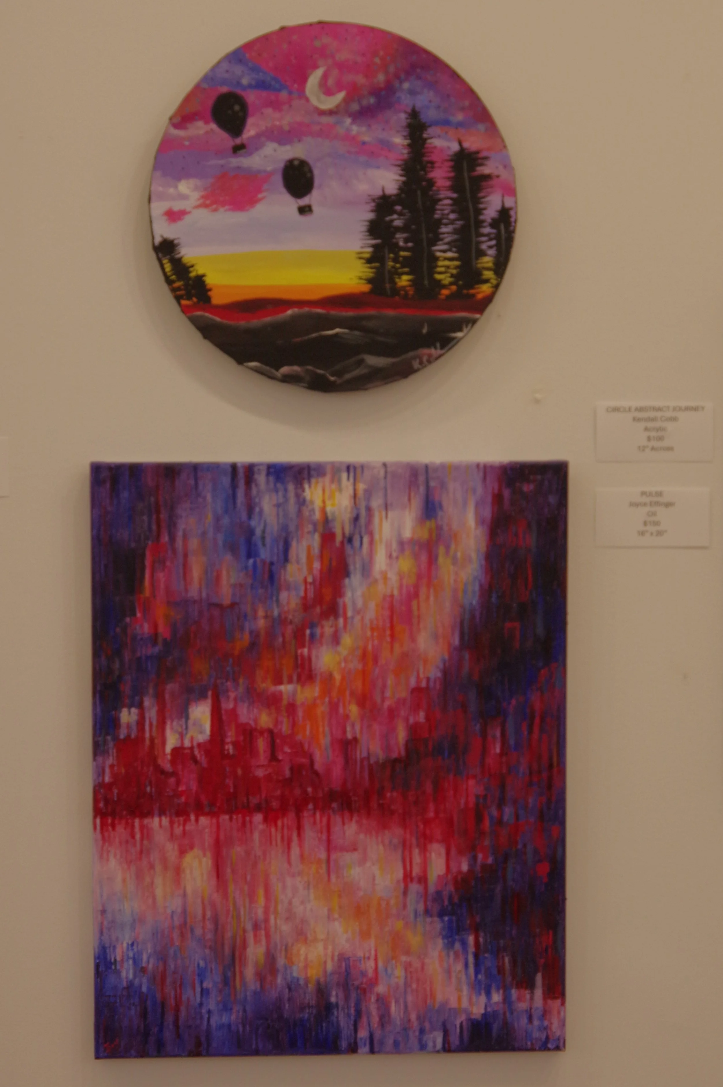 Two paintings: the top painting depicts hot air balloons flying over a landscape at sunset with a crescent moon and a pink, purple, and blue sky. The bottom painting is an abstract cityscape reflection in water, using vibrant reds, pinks, purples, and blues.