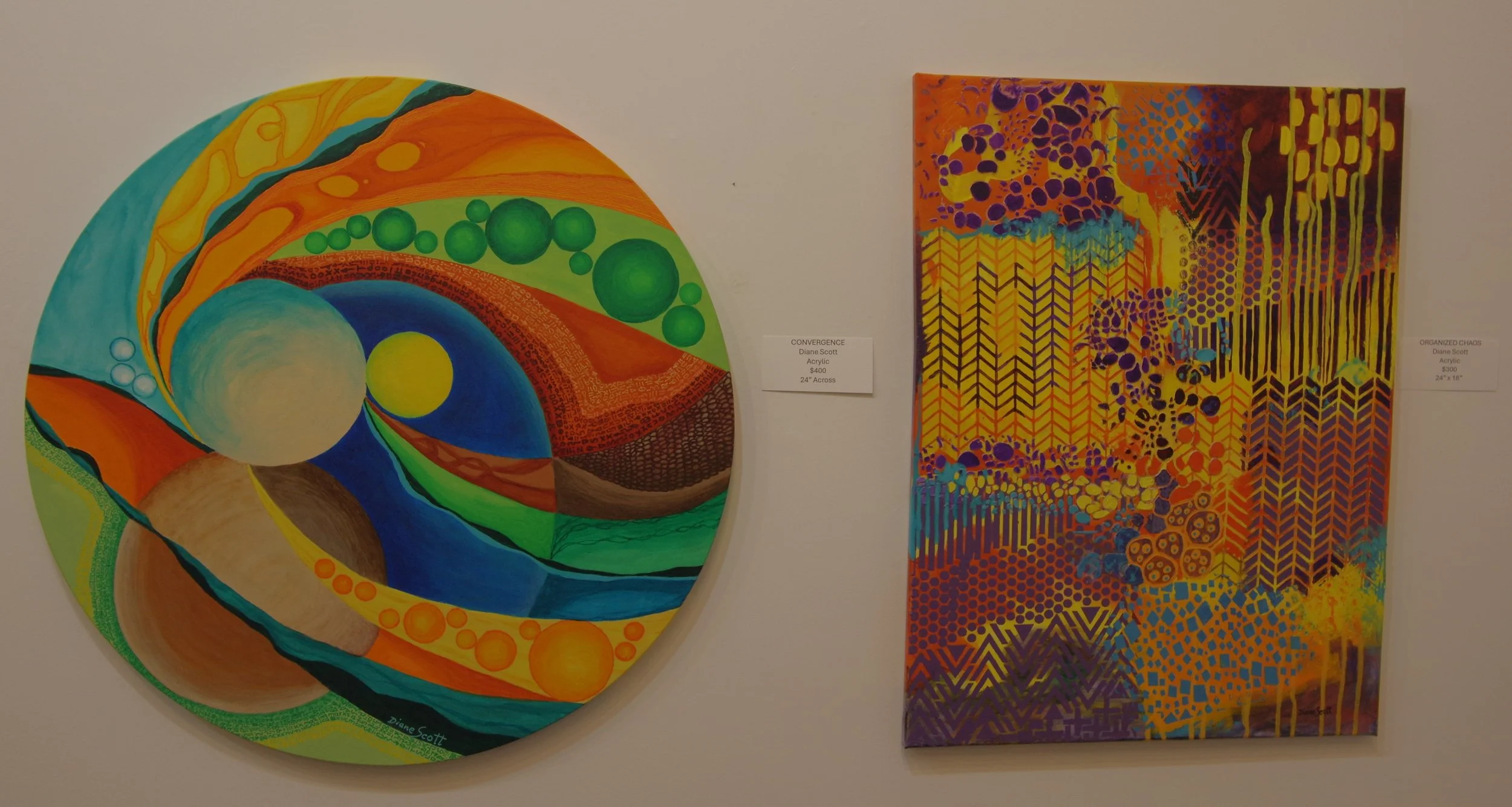 Two colorful abstract paintings on a wall, one circular and one rectangular, with vibrant colors and intricate patterns.