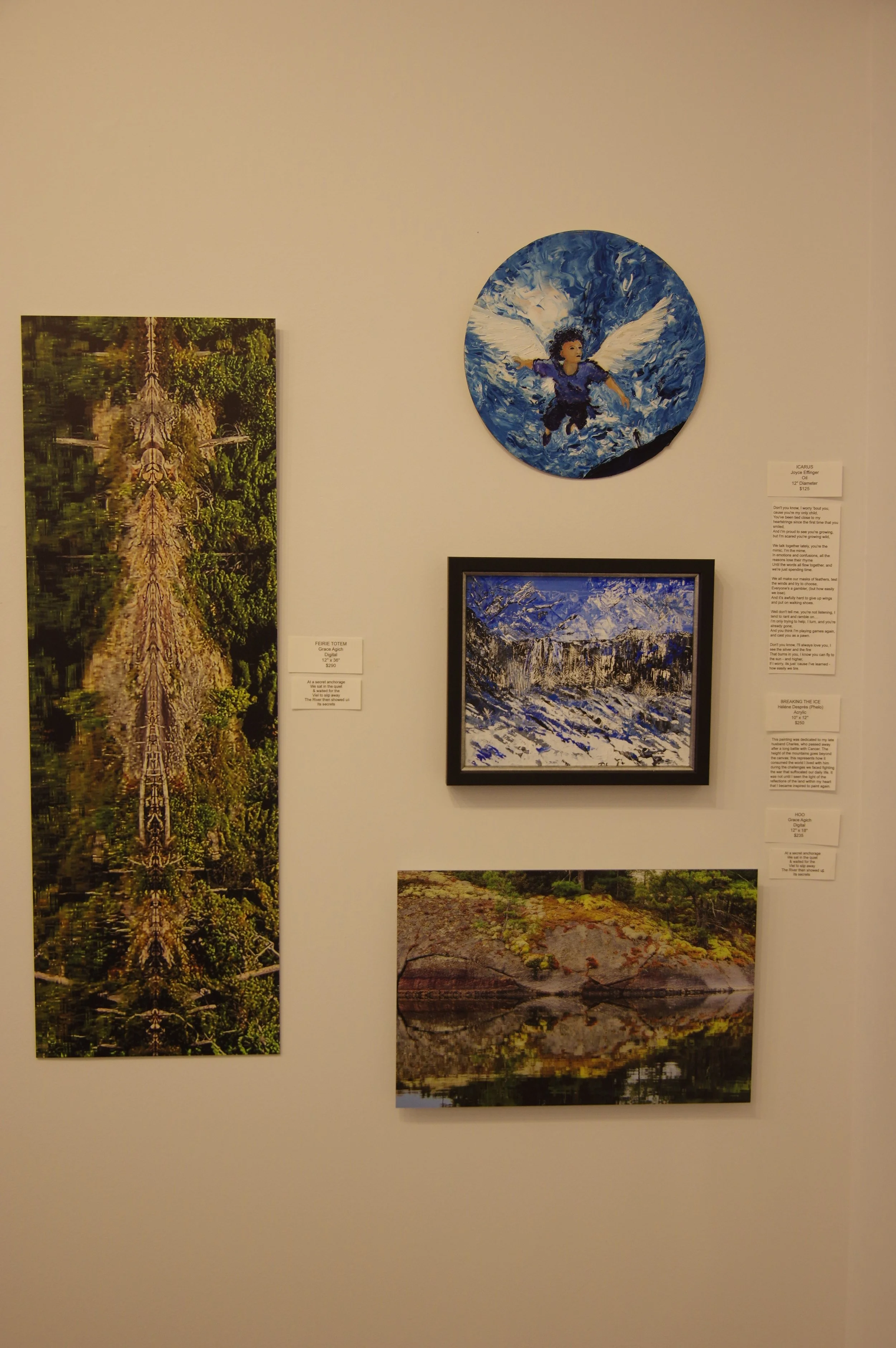 Gallery wall featuring five art pieces: a vertical distorted digital art forest and river scene, a round painting of a winged child flying over water, a horizontal painting of snow-covered mountains, and a horizontal landscape of a rocky shoreline with water reflections, all accompanied by informational plaques.