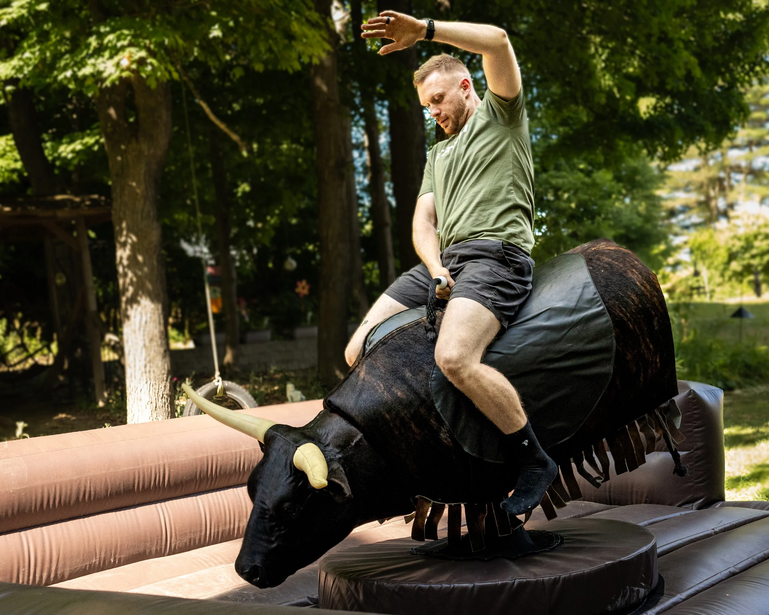 A man riding a S&W Mobile Entertainment's mechanical bull outdoors.