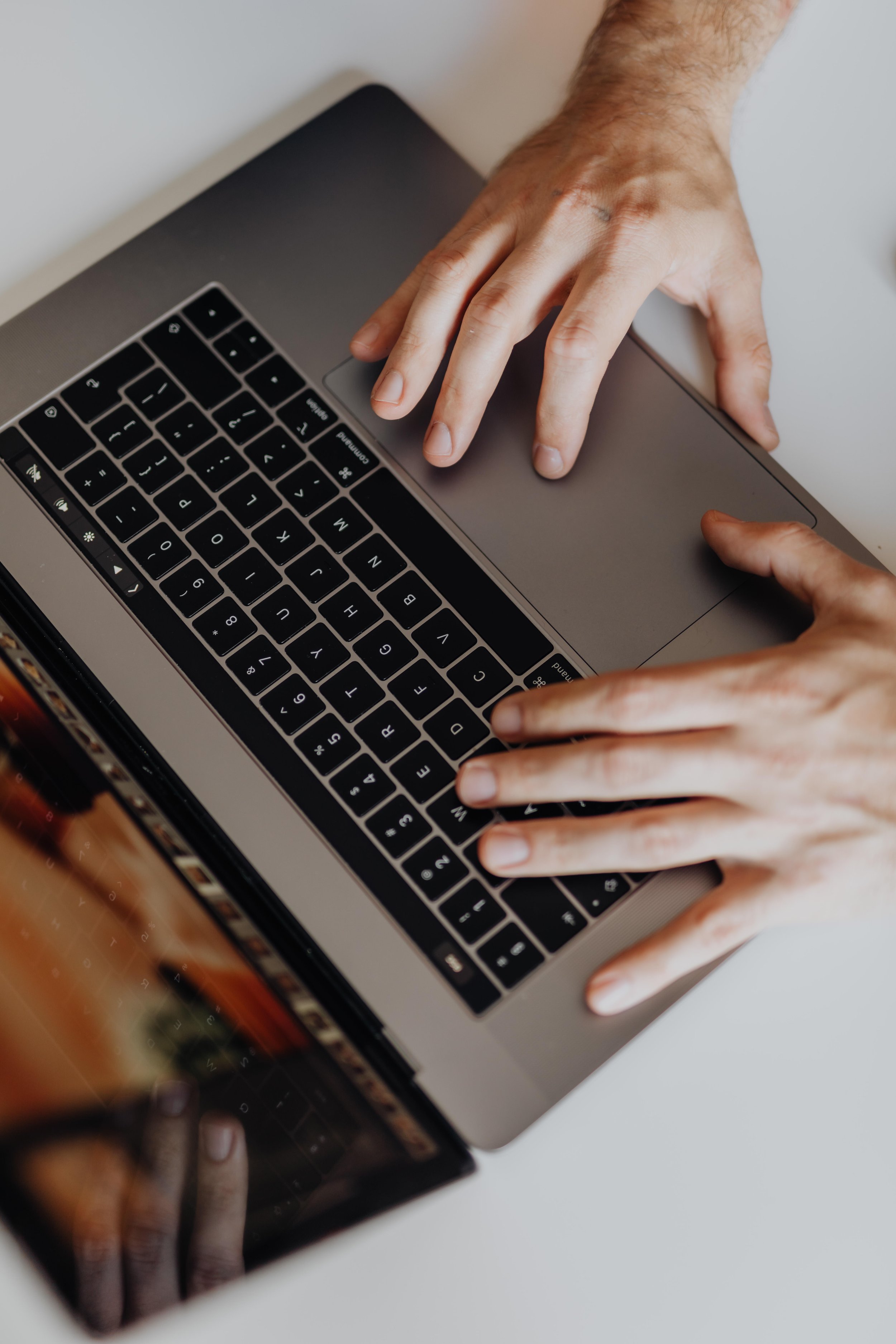 Person typing on a laptop with a numerically-focused, black keyboard and a large touchpad.