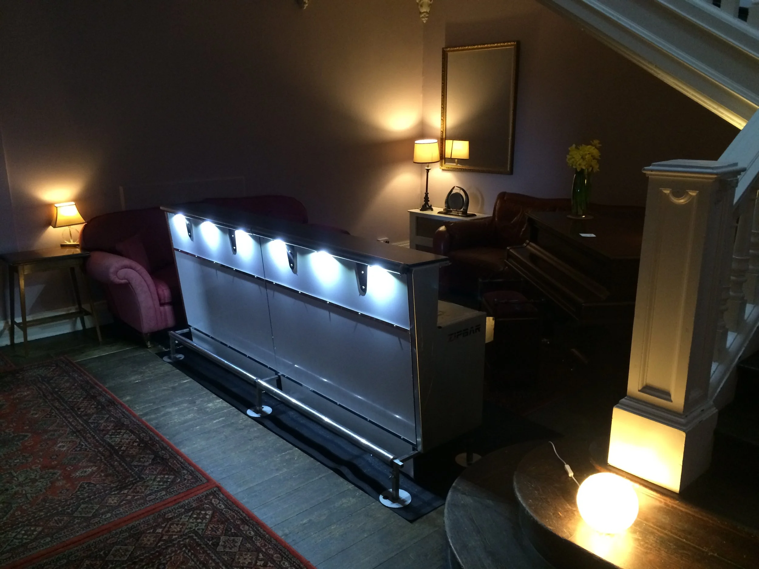 Living room with a mobile bar, a piano, and warm ambient lighting.