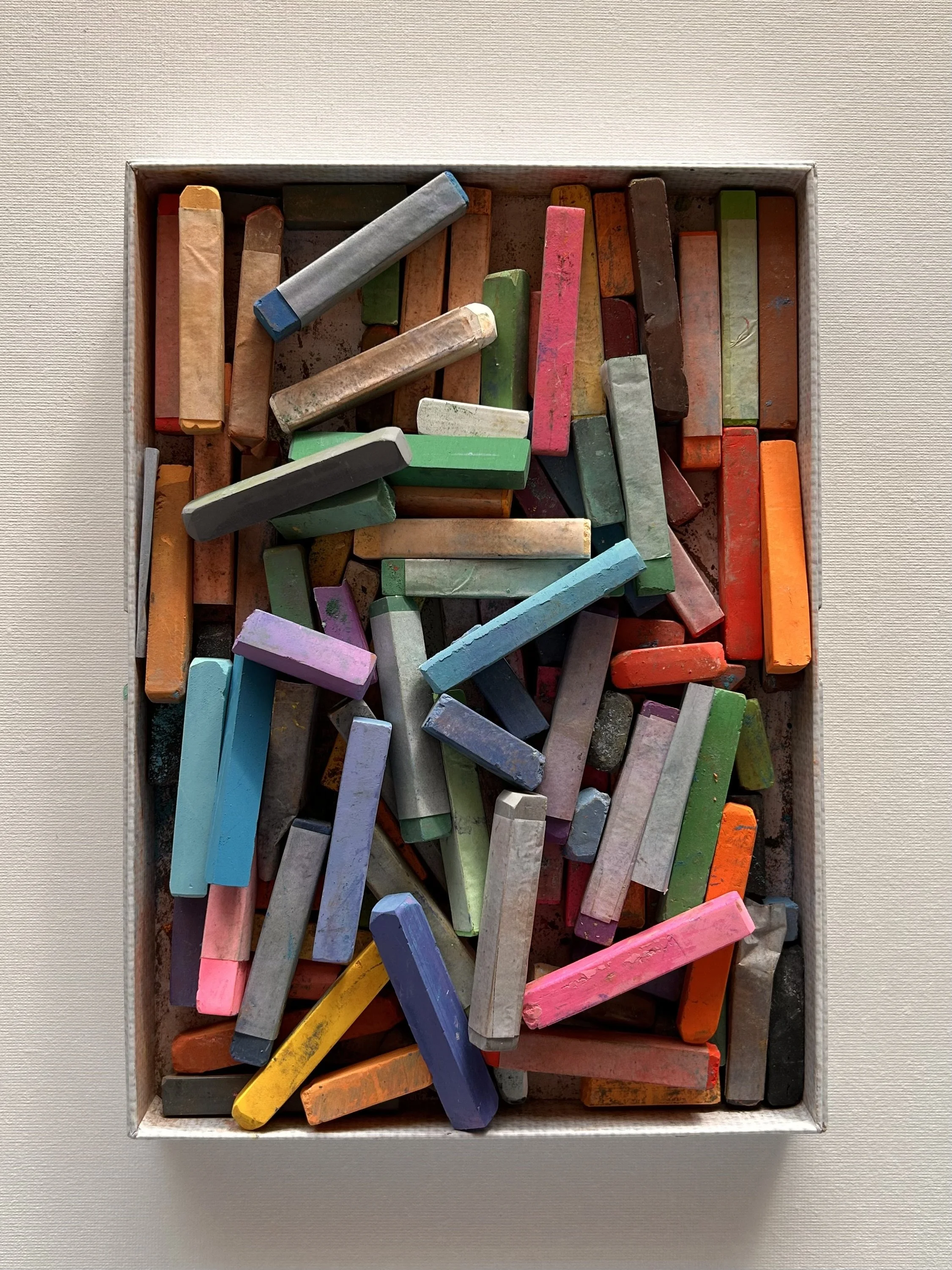 Top view of a box filled with colorful chalk sticks.