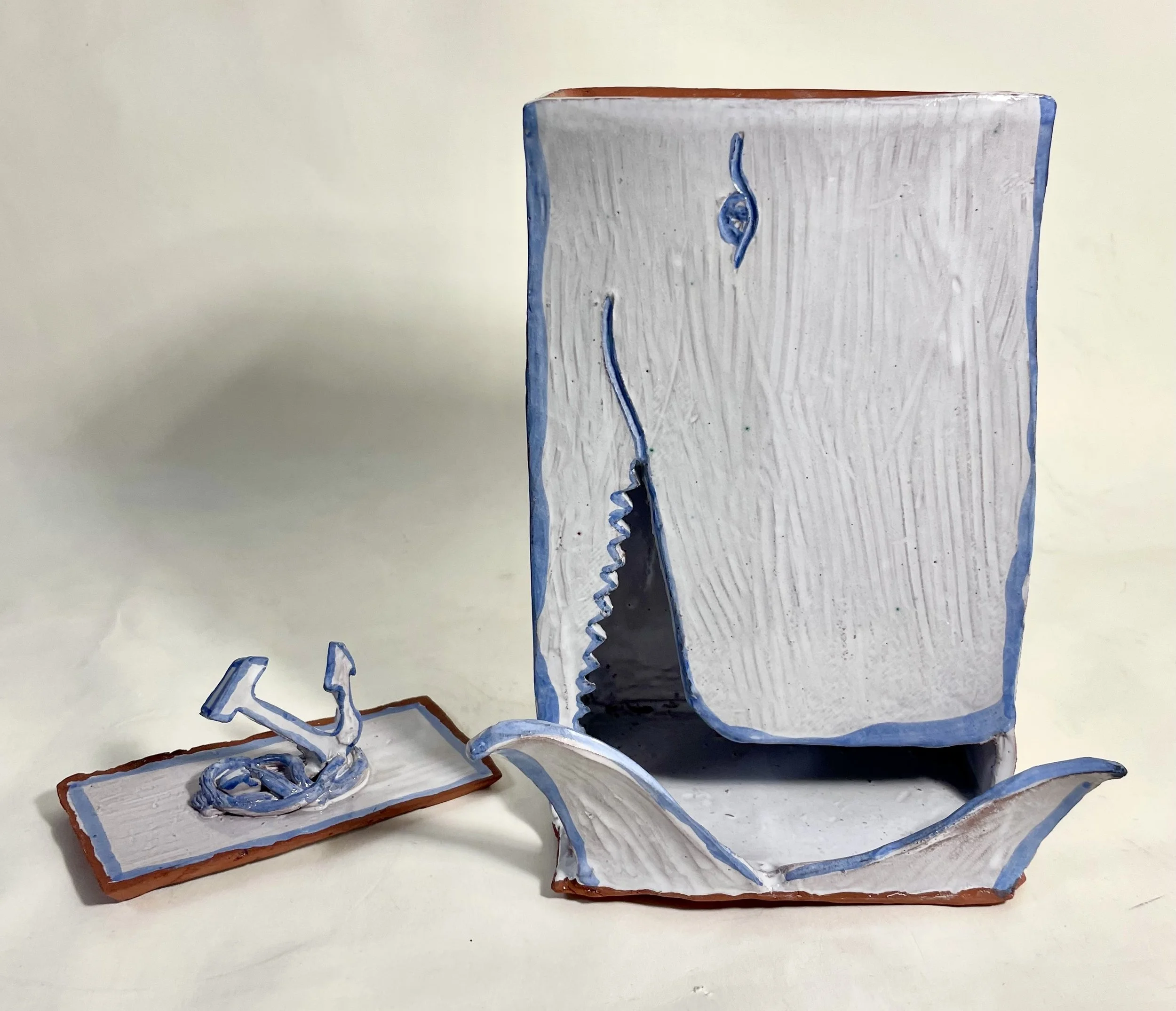 Ceramic art sculptures resembling a whale and anchor, painted in white, blue, black, and brown.