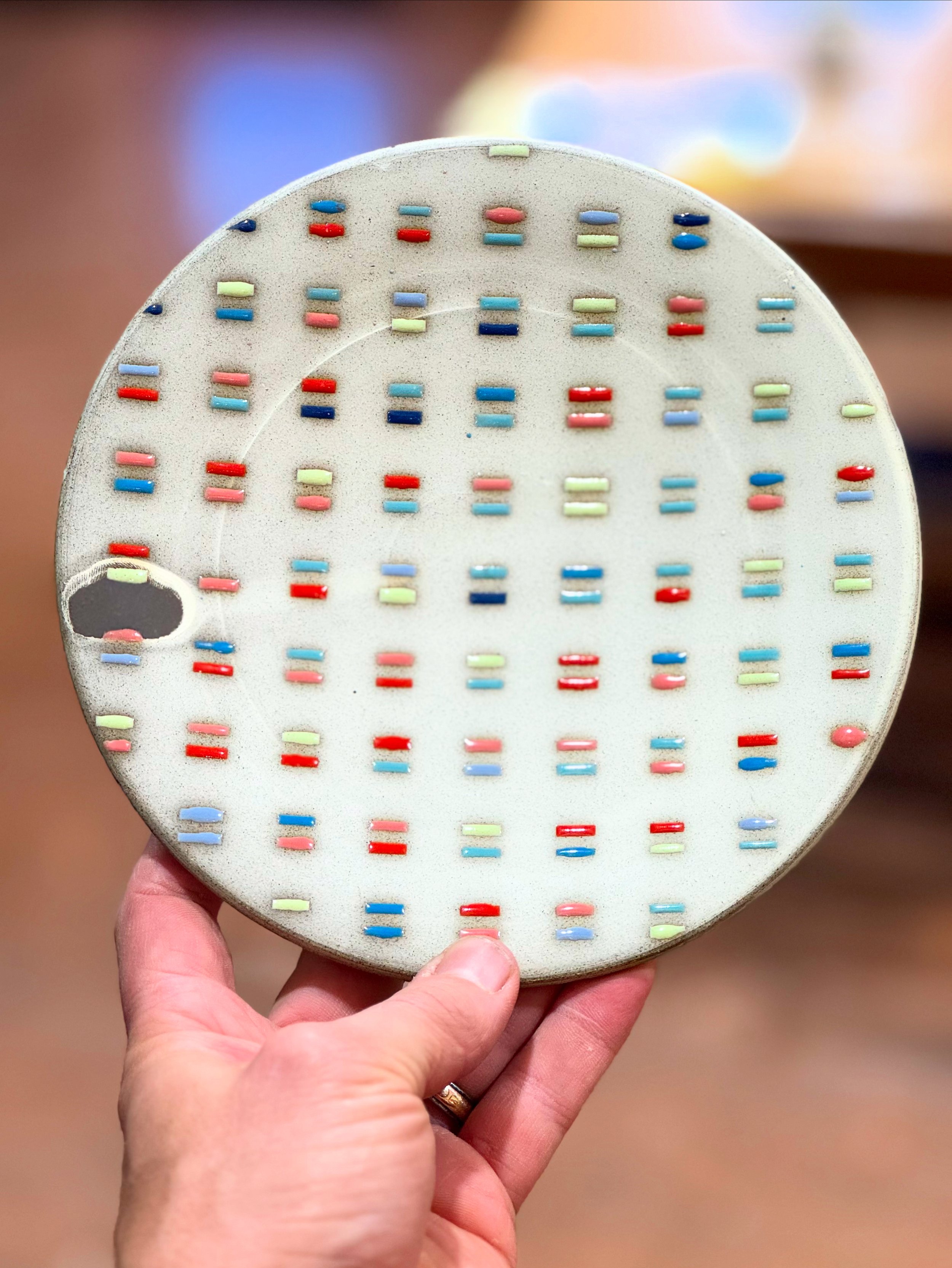 A person holding a circular orthodontic device with multiple colorful rubber bands. The device is used for dental orthodontic treatment.