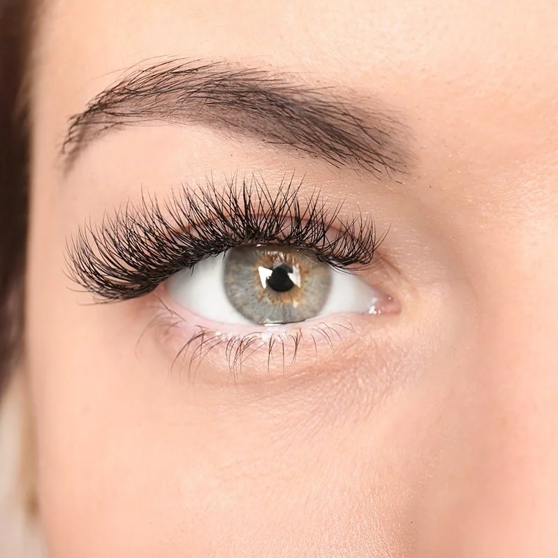 Close-up of a woman's eye with long, thick eyelashes and a hazel iris.