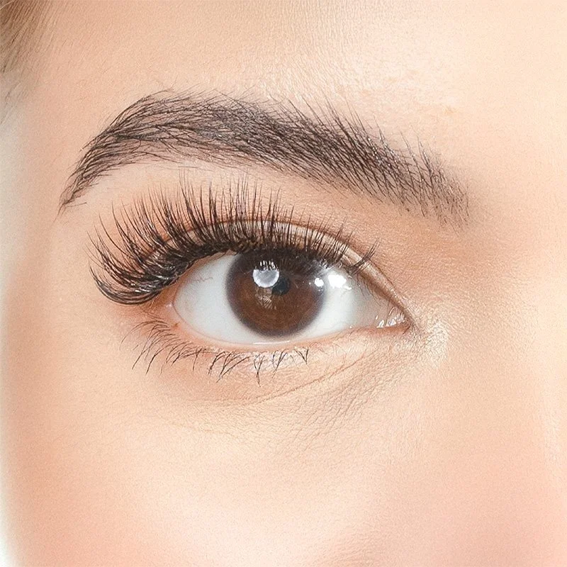 Close-up of a woman's eye with makeup, including long eyelashes, well-defined eyebrow, and smooth skin around the eye.