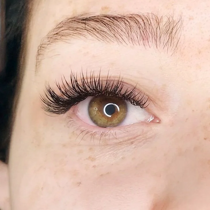 Close-up of a person’s eye with long, dark eyelashes and light brown iris.