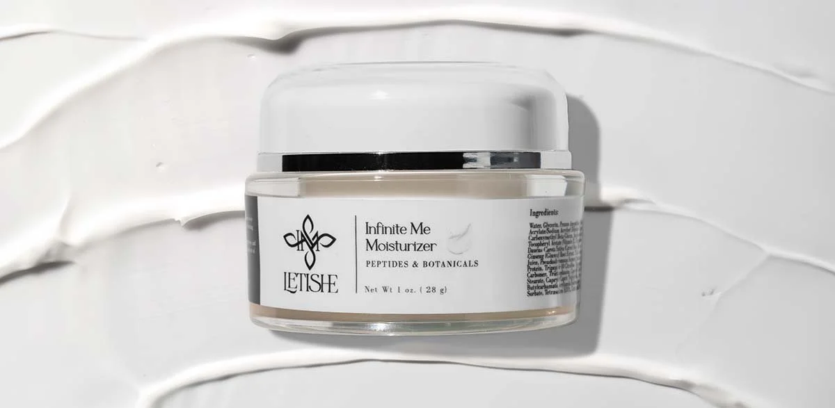 A jar of Letisee Infinite Me Moisturizer with a black, white, and beige label, placed on a textured white background.