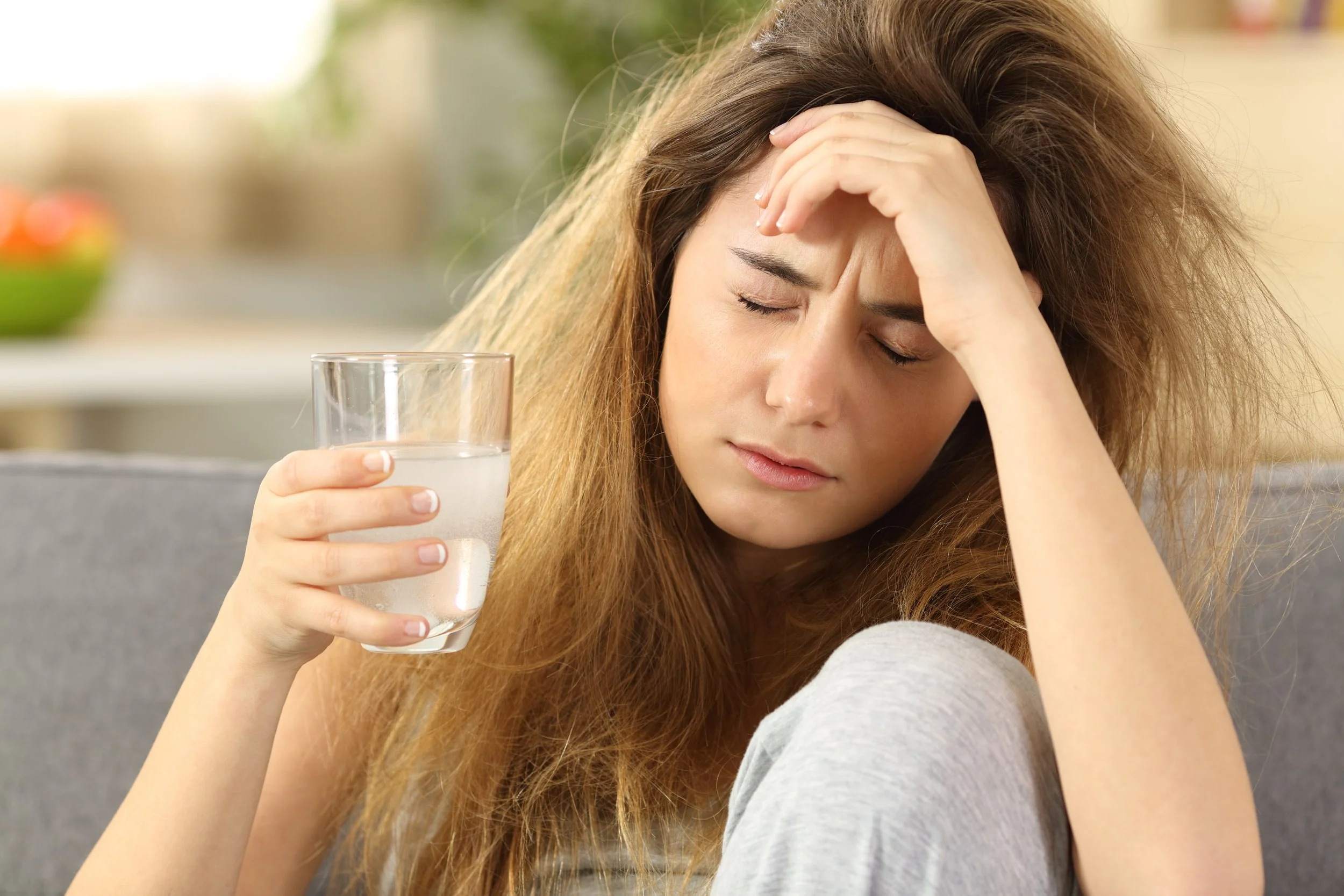 Women holding her head in pain while drinking ice water