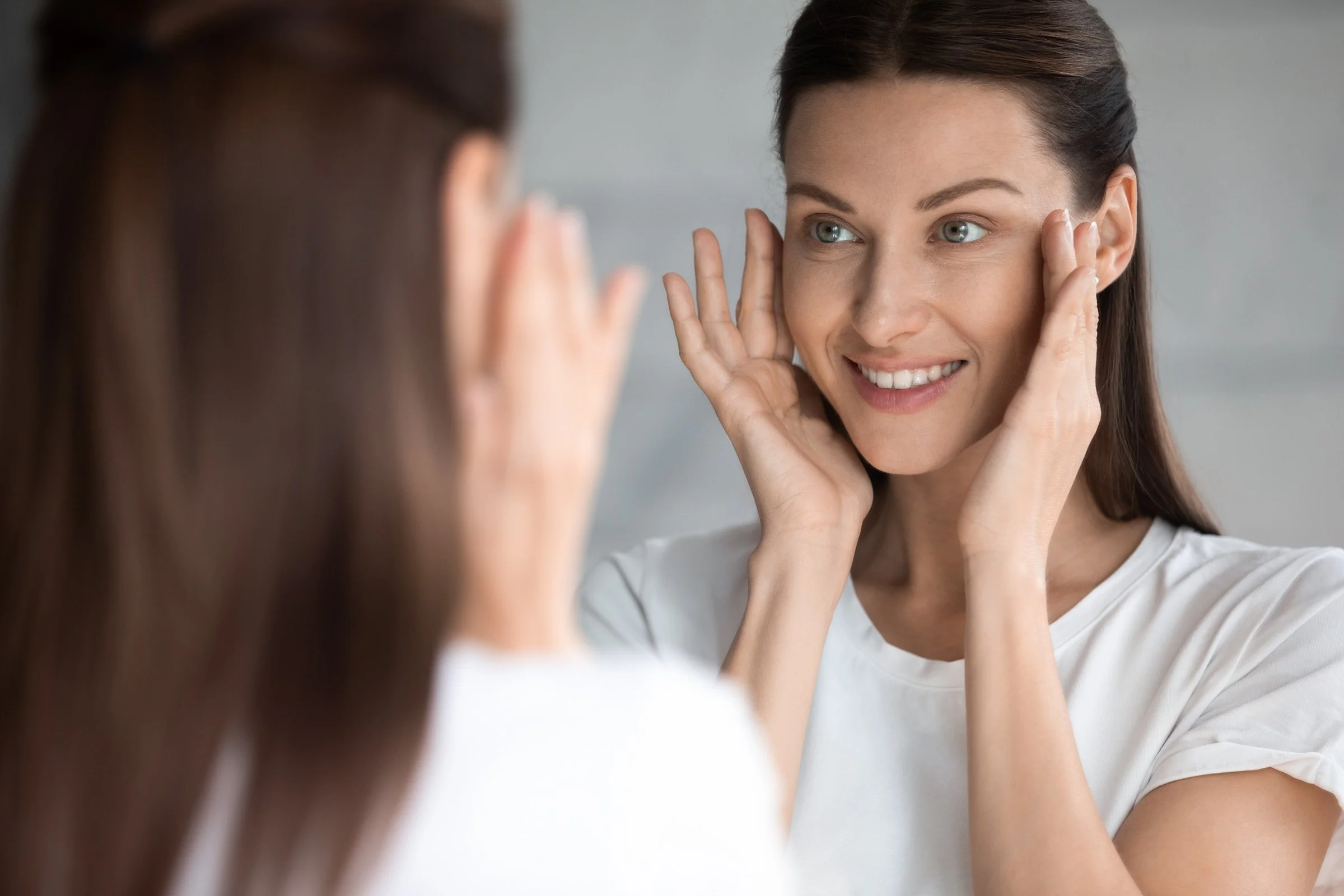 woman looking at her skin in the mirror