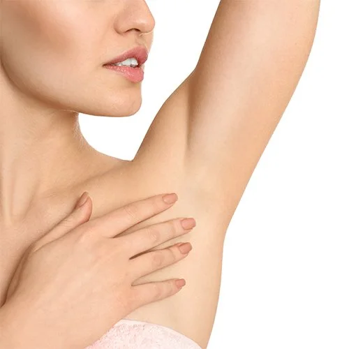 A woman inspecting her underarm skin with her right arm raised and her left hand touching her chest.